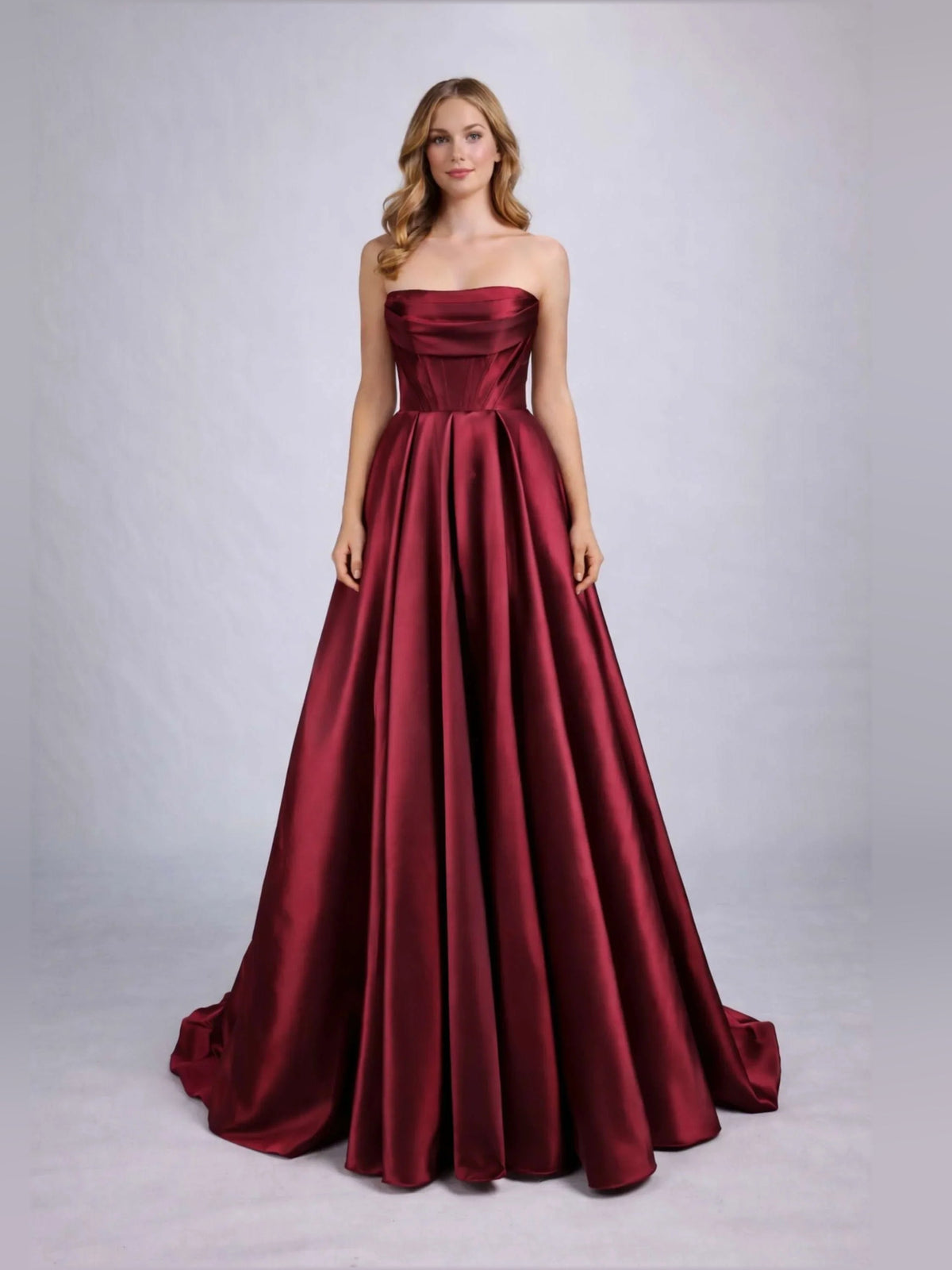 Burgundy strapless corset formal dress with fitted bodice and full pleated floor-length skirt