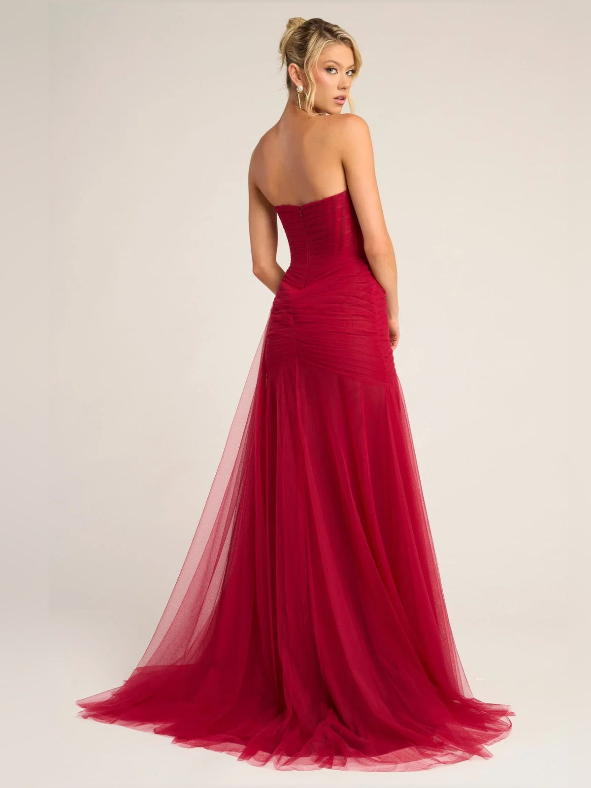 Red strapless sweetheart mermaid formal dress, back/side view with sheer tulle hem.