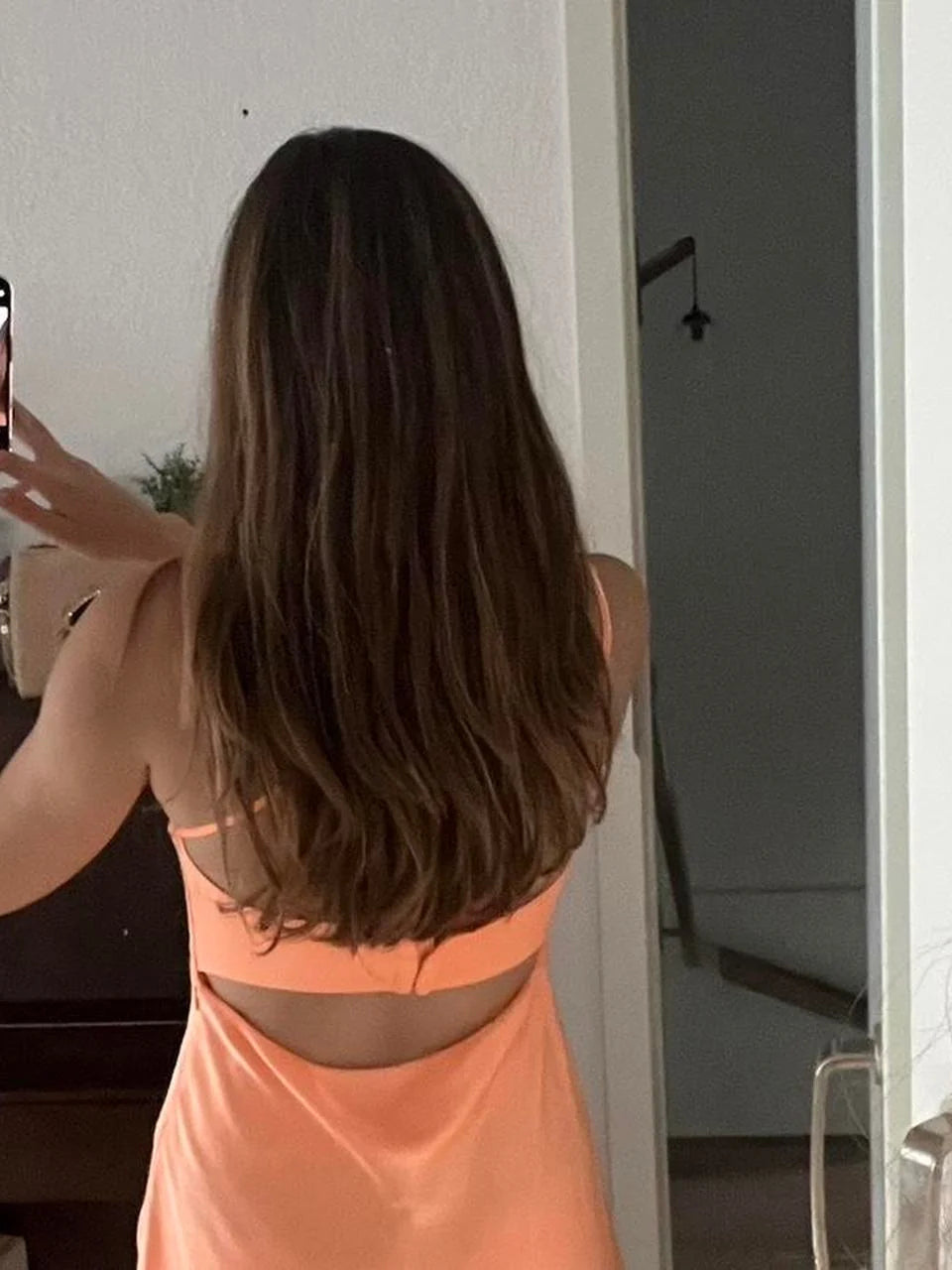 Orange satin mini slip dress with open back and thin straps, back view.