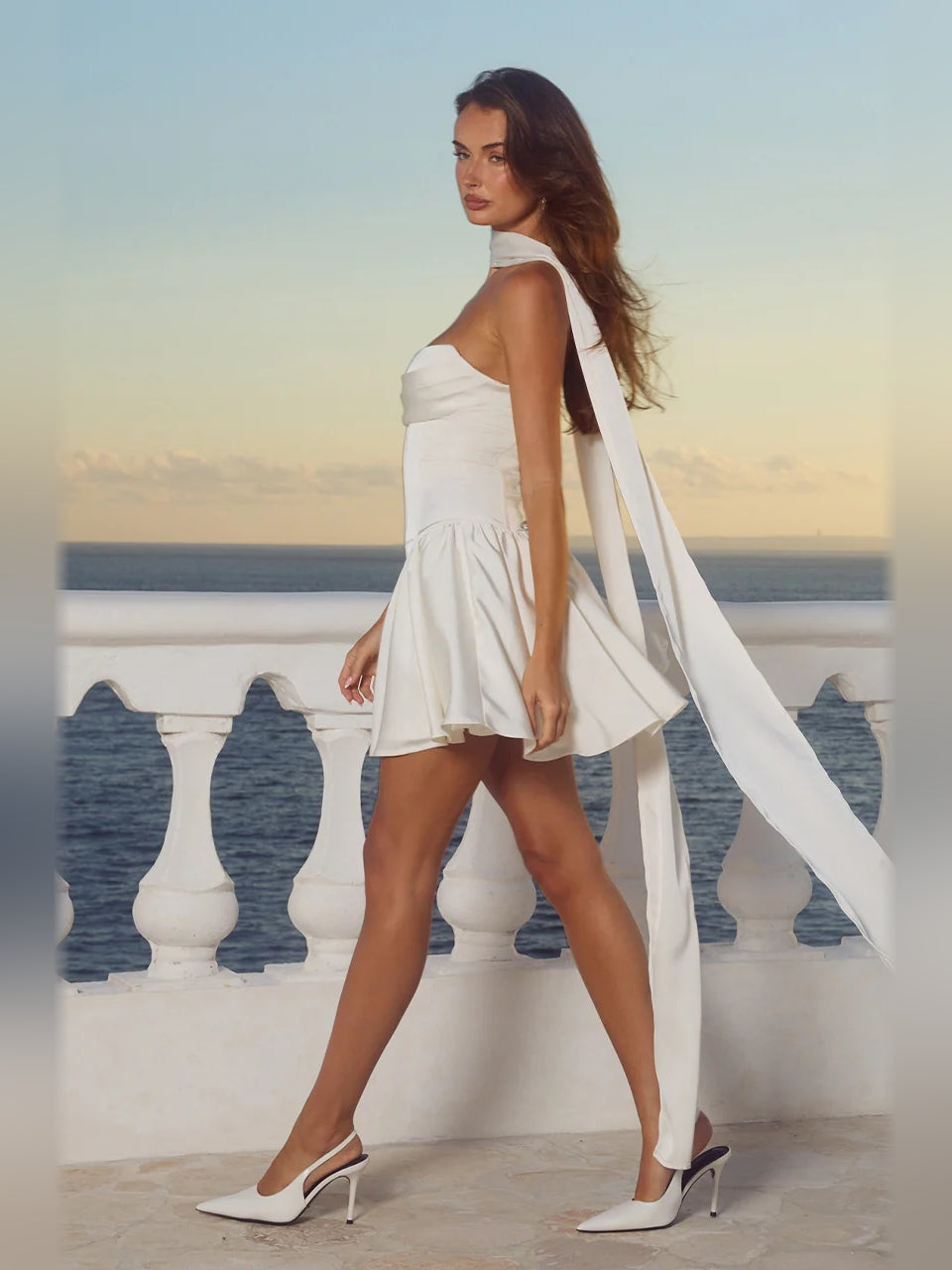 Ivory strapless mini dress with high halter neckline and flowing draped back panel, side view