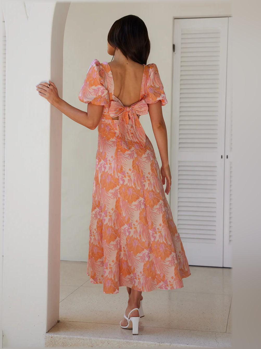 Back view of coral-pink midi formal dress, open square back with bow tie, puff sleeves