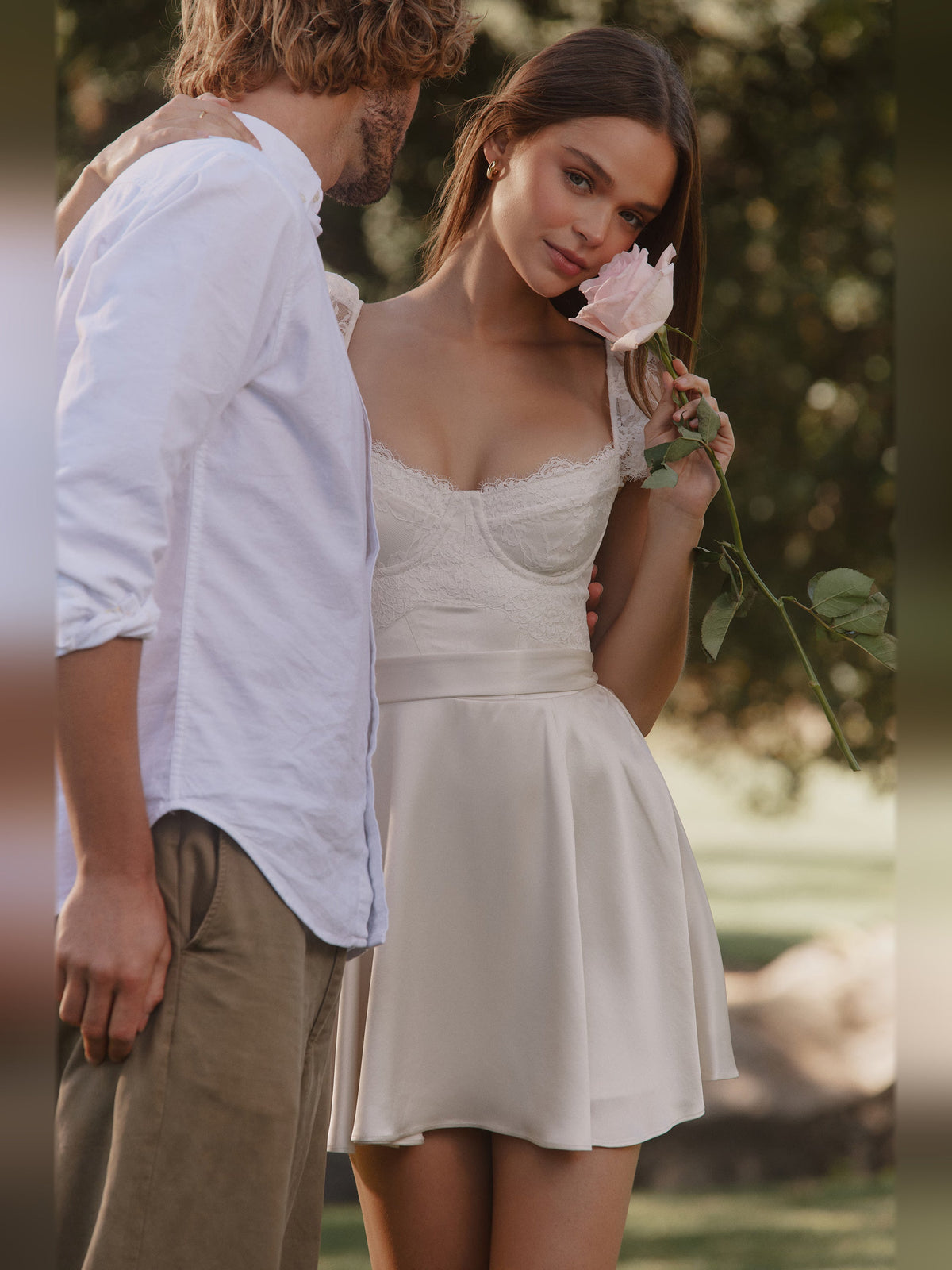 White mini satin homecoming dress with lace sleeves and gathered pleated skirt