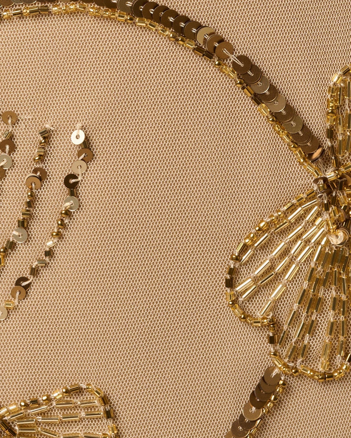 Close-up of gold beaded floral and chain embroidery on sheer mesh fabric