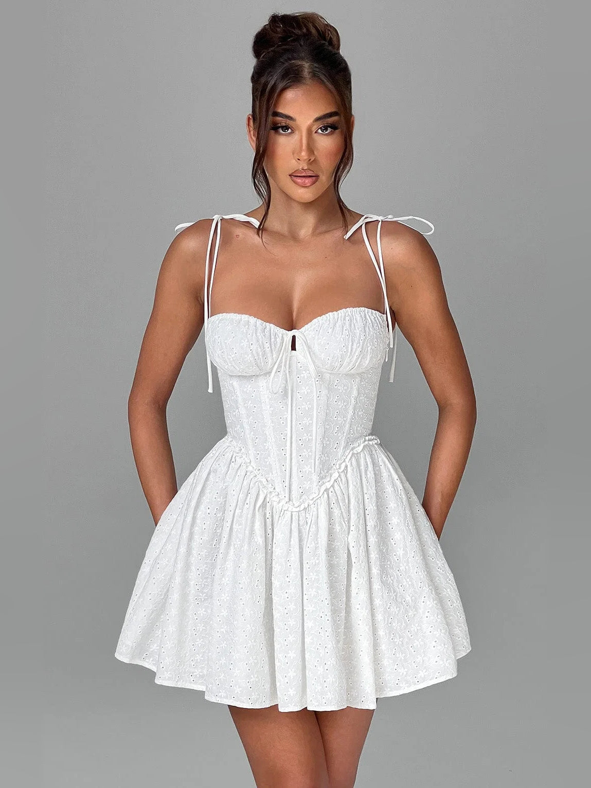 Ivory mini dress with sweetheart neckline, corset seams, tie straps, and tiered skirt