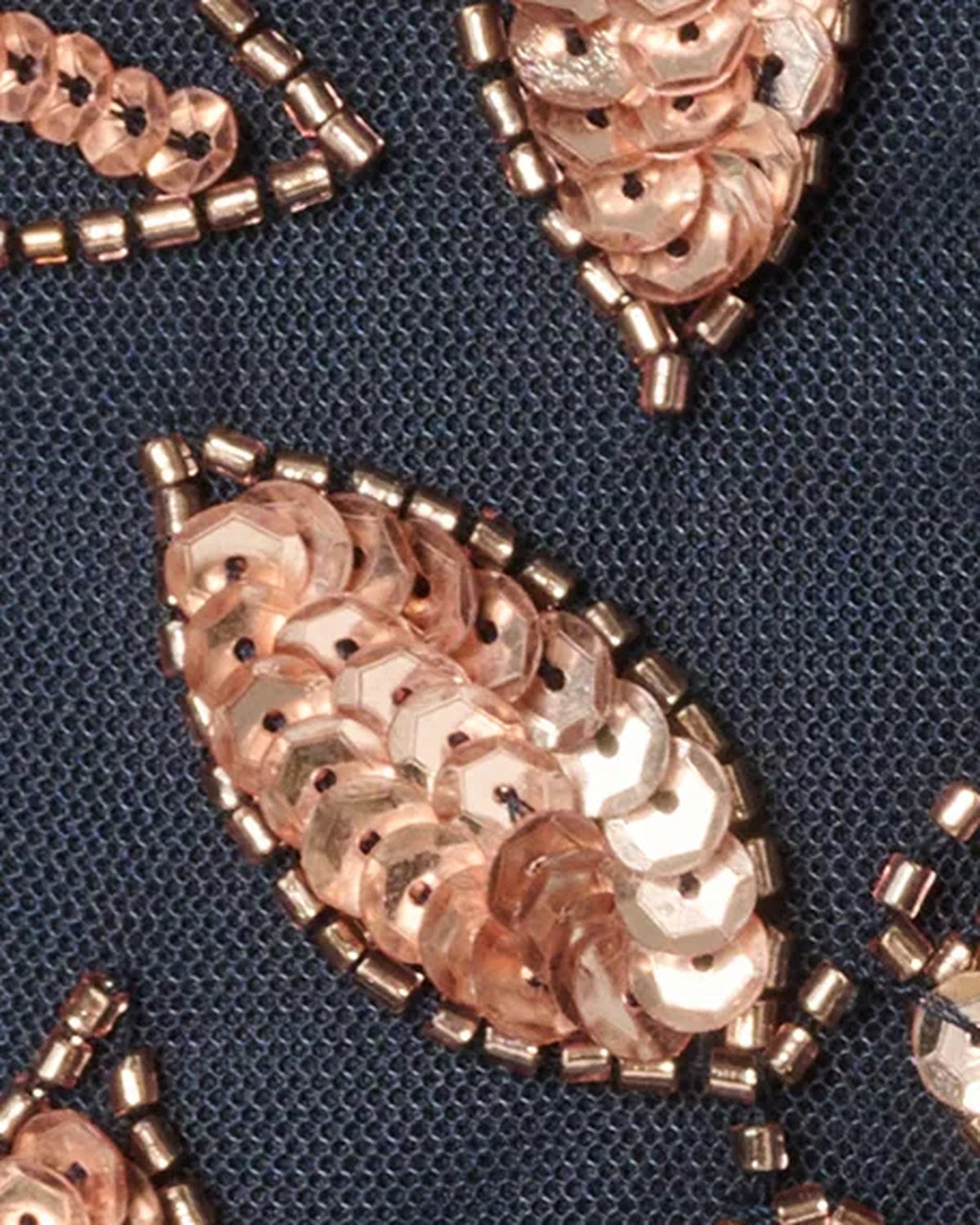 Close-up of rose-gold floral beaded embellishment on navy fabric