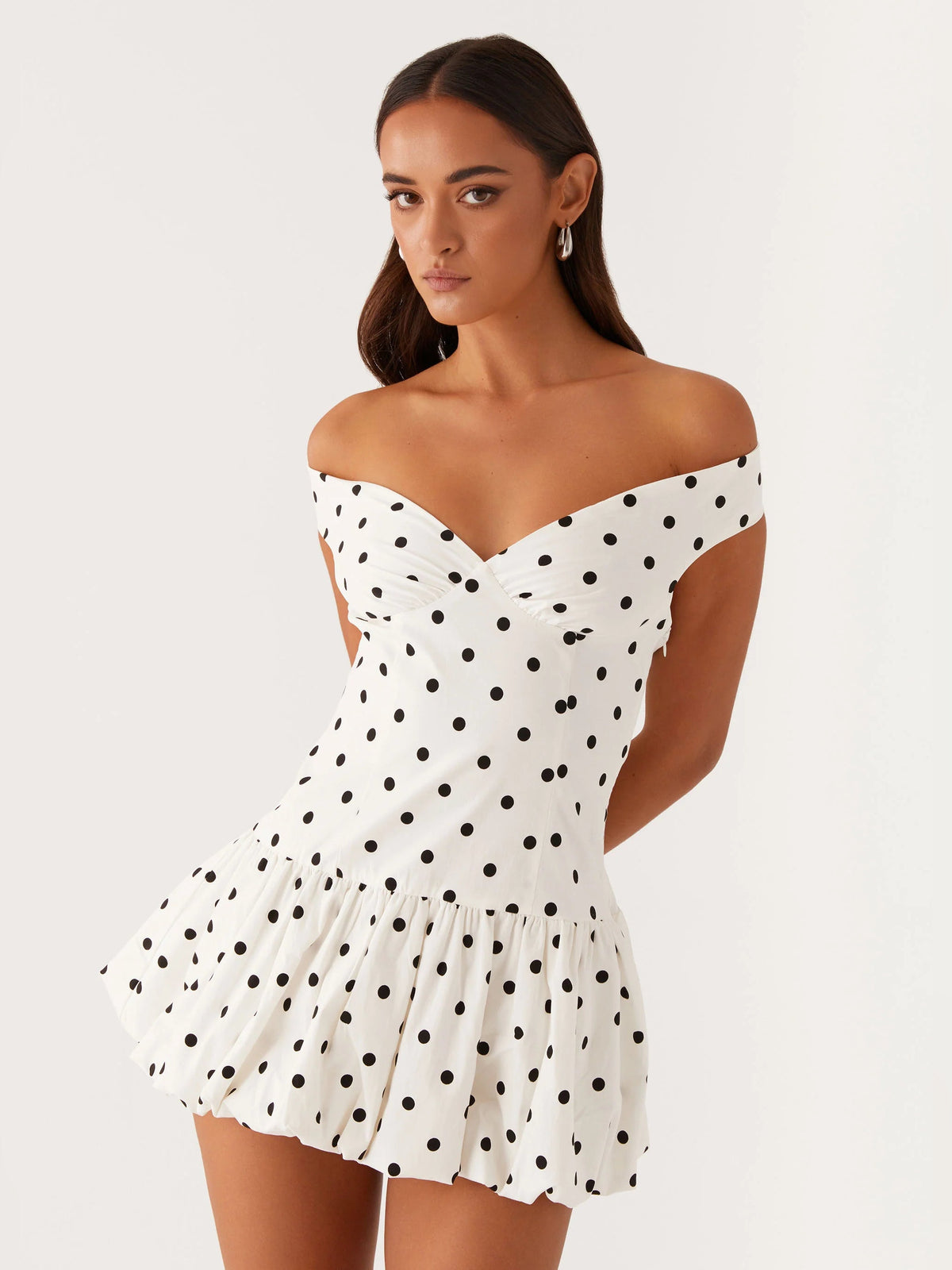 Off-shoulder mini dress front view in white with black polka dots, sweetheart neckline, ruffled hem