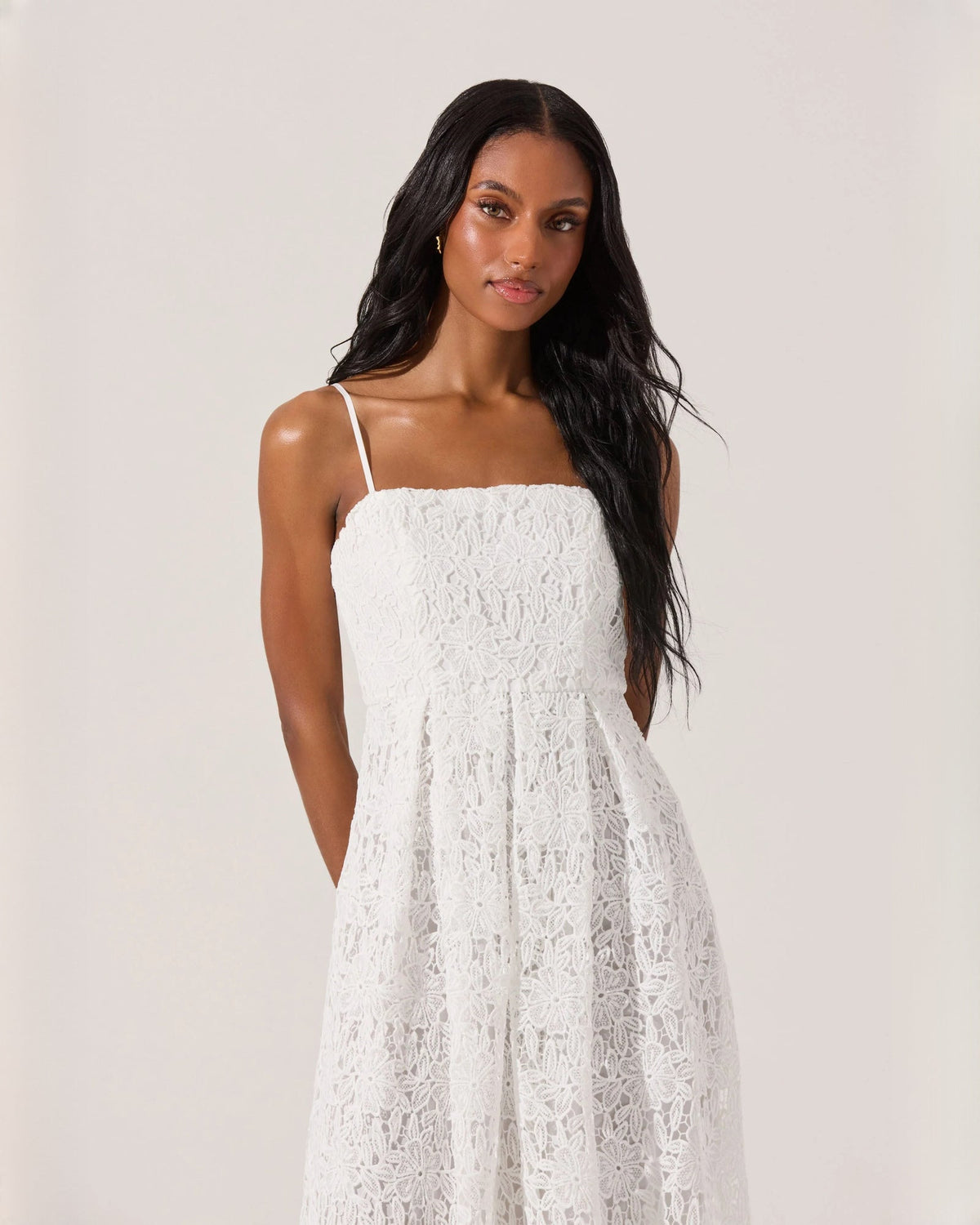 Front view of white sleeveless A-line midi dress with spaghetti straps and lace texture