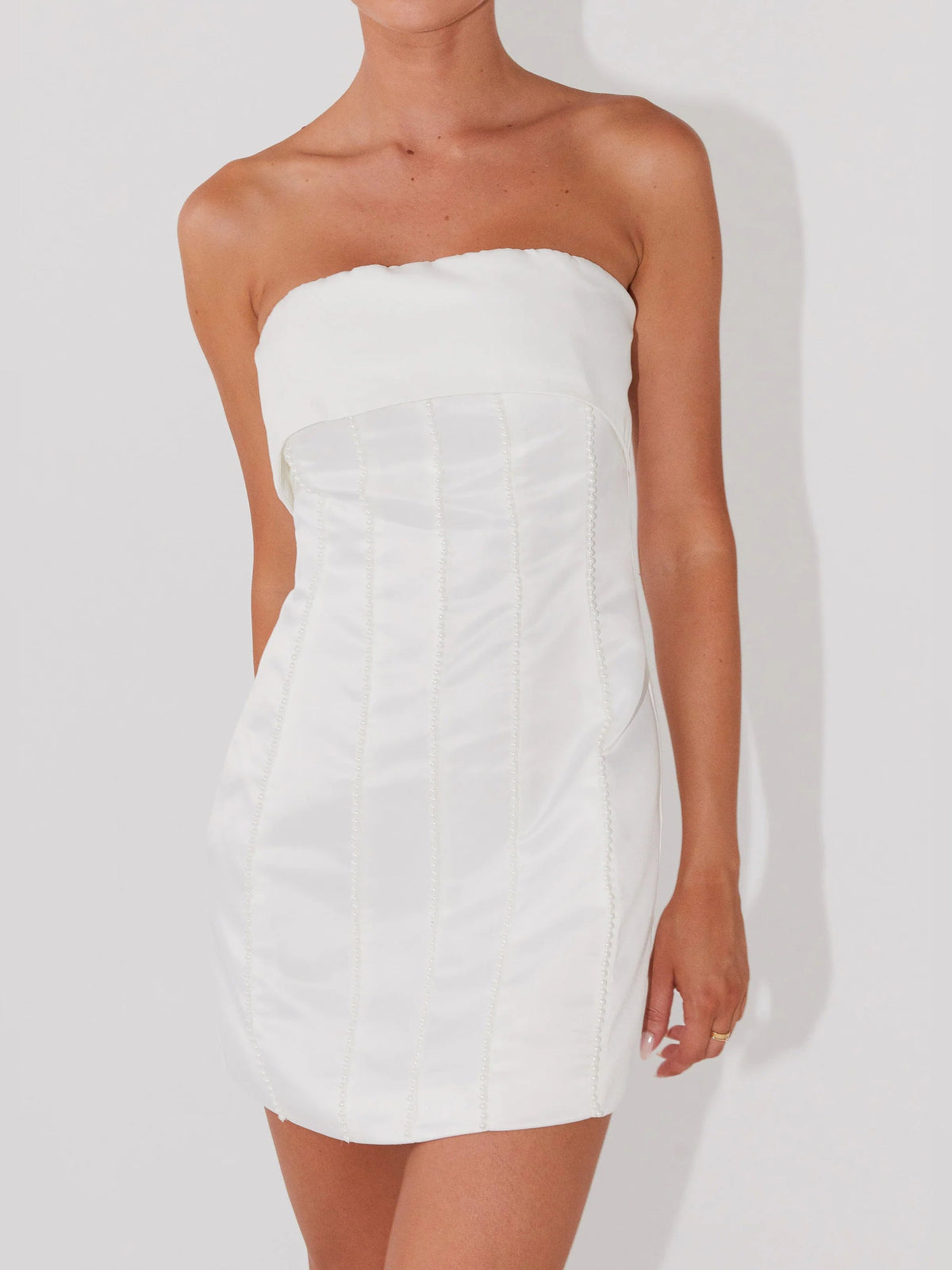 Pearl strapless mini dress close-up showing structured corset seams and pleated bodice
