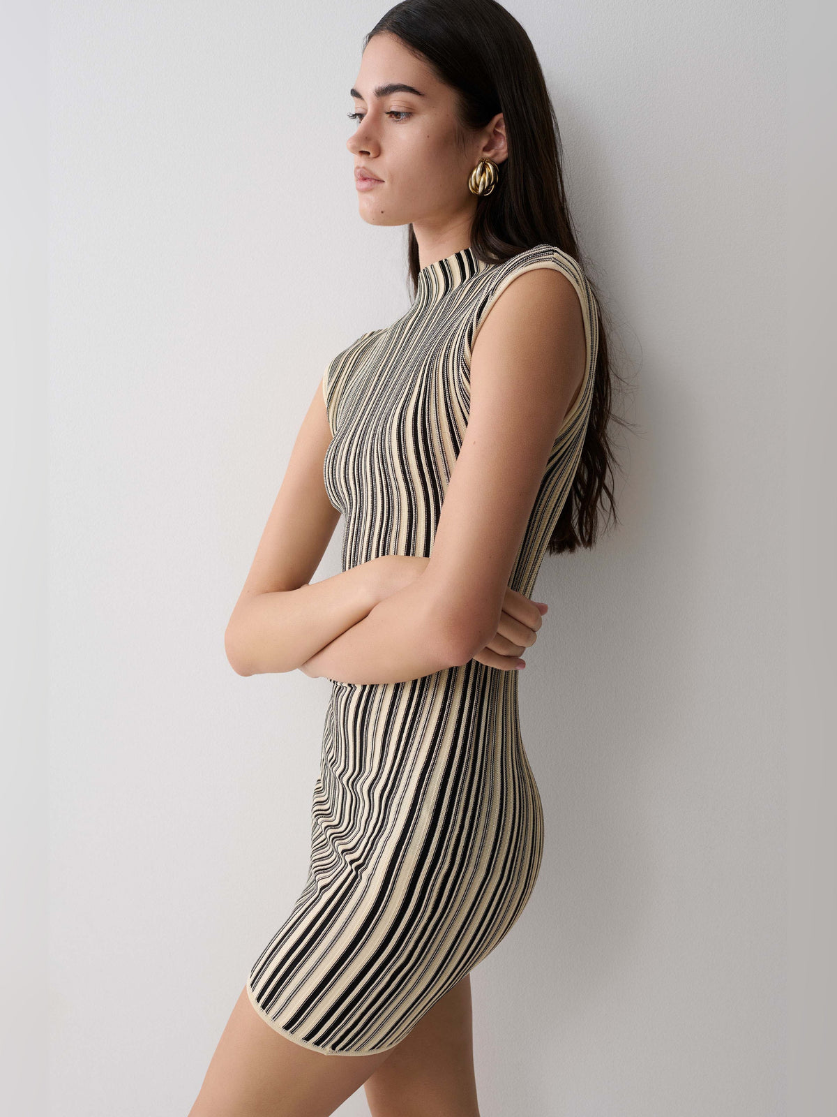 Sleeveless ivory mini dress with vertical black and gold stripes, high neck, sleeveless fitted