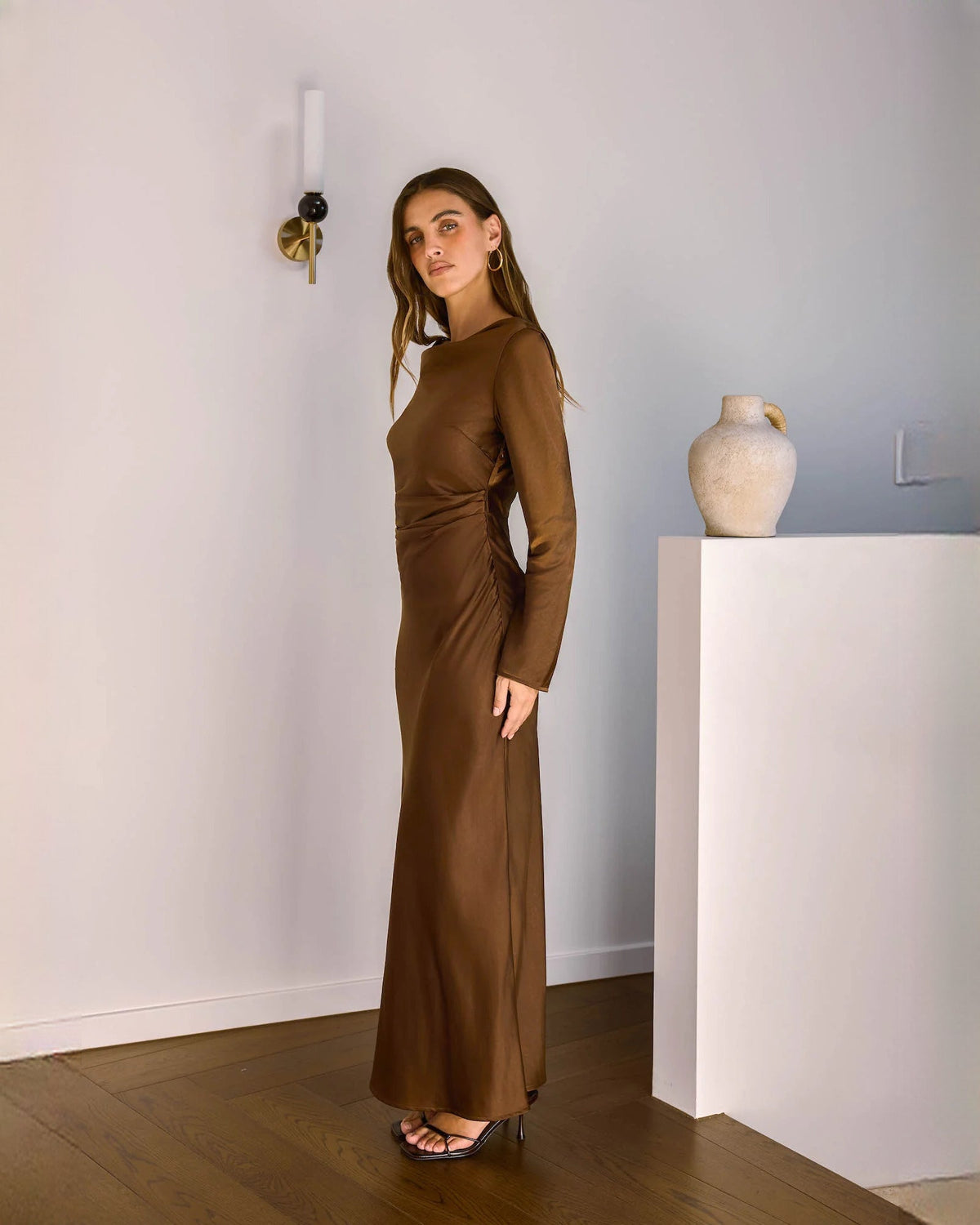 Chocolate brown satin maxi dress viewed in profile with long sleeves and long A-line skirt