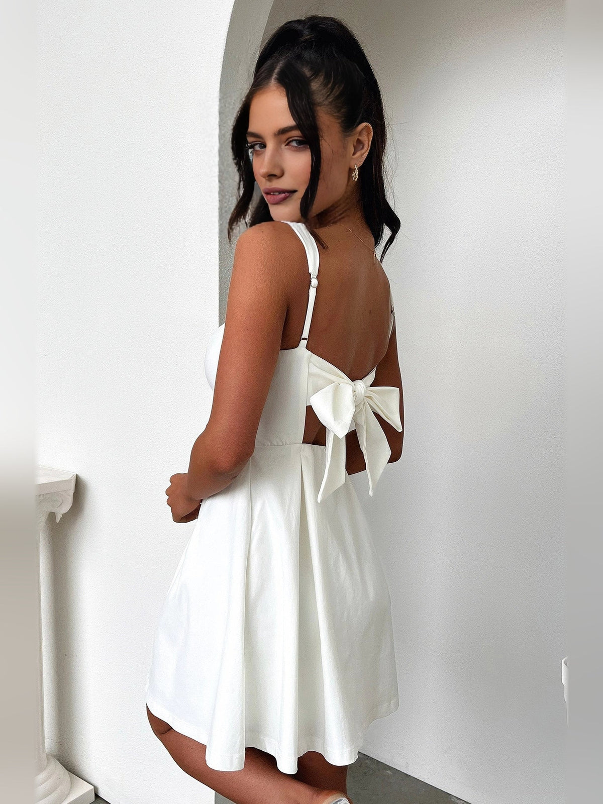 Backless ivory mini dress with square straps and tied bow across the back