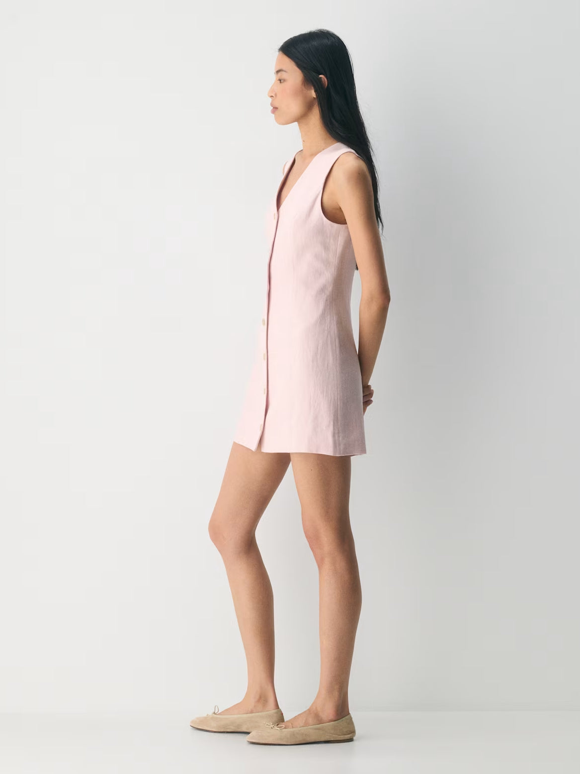 Light pink sleeveless mini dress with V-neck and front buttons, side view