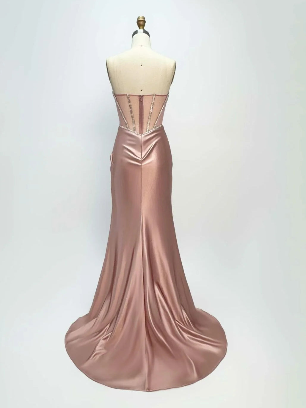 Dusty pink satin mermaid prom dress on mannequin with draped skirt and flared hem