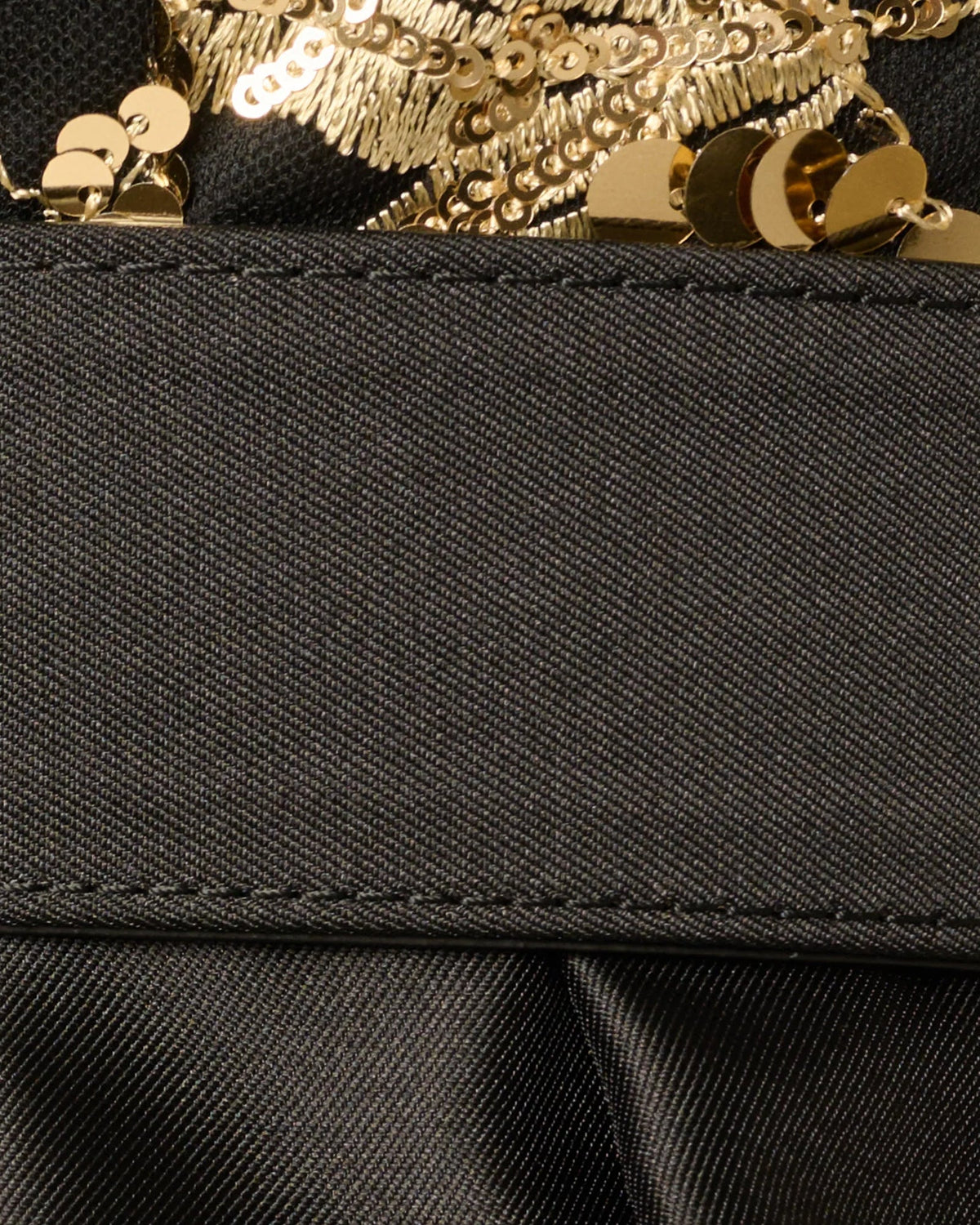 Gold buckle and embroidered trim detail on black waist belt
