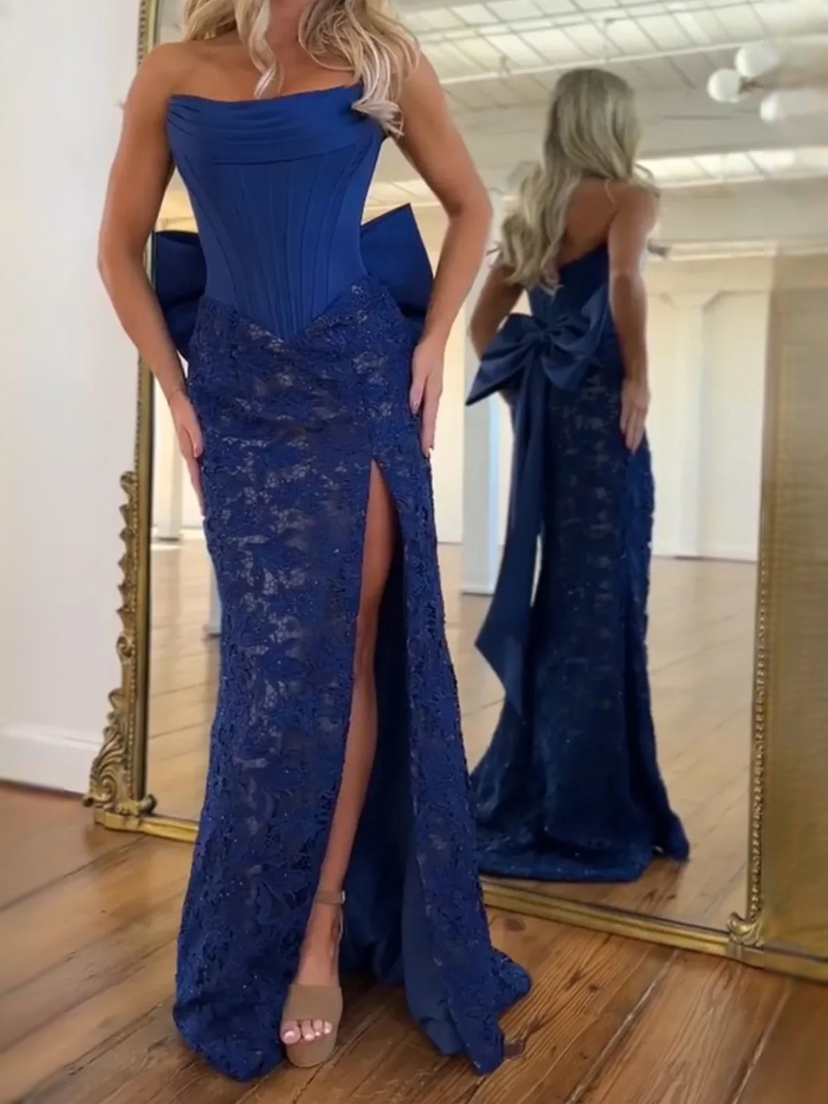 Dark blue strapless mermaid prom dress with large back bow, lace overlay, and front slit