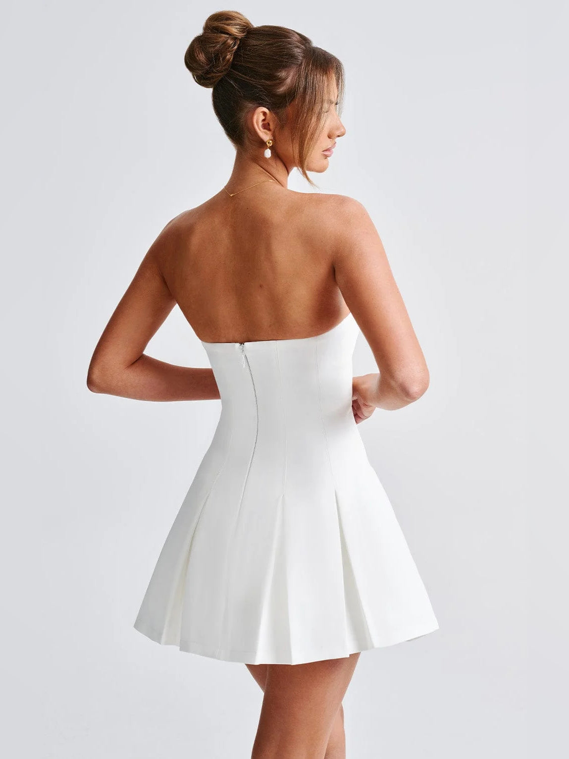 Ivory strapless mini dress from back, showing fitted waist seam and pleated skirt