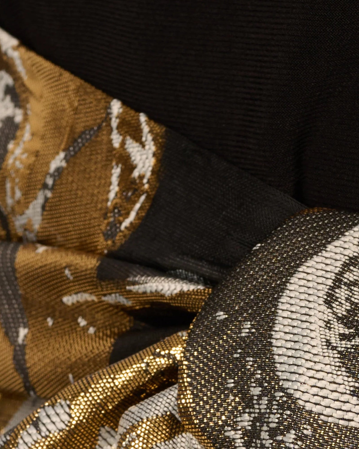 Close-up of gold, white, and dark floral fabric with sparkling woven texture