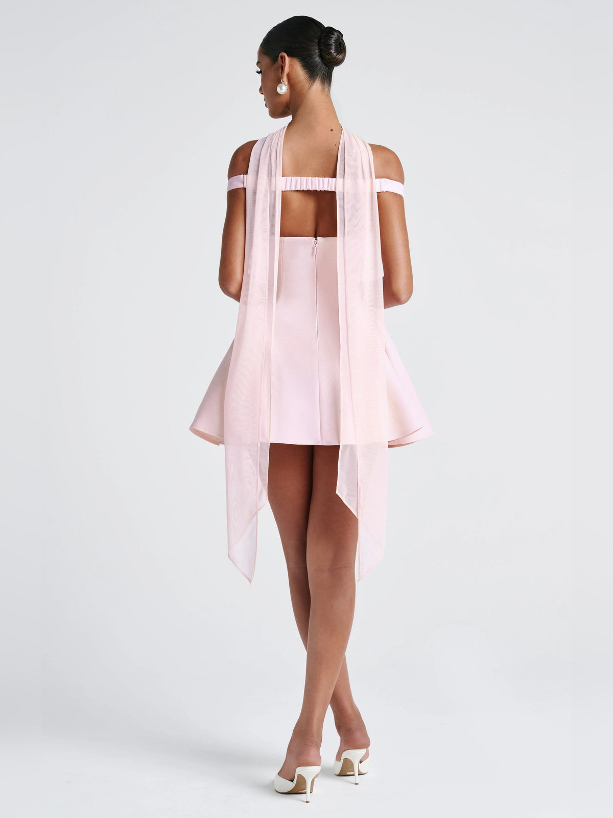 Back view of blush mini dress: sheer overlay straps, open back, layered tulle drape and flared skirt.