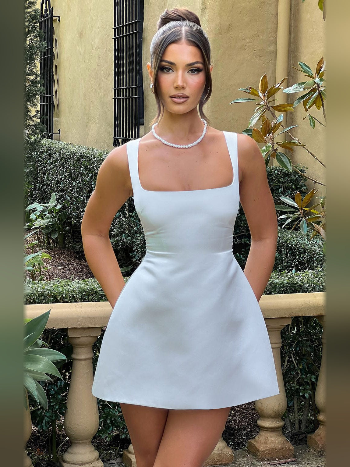 Ivory mini homecoming dress with pearl necklace and gray headband; square neck