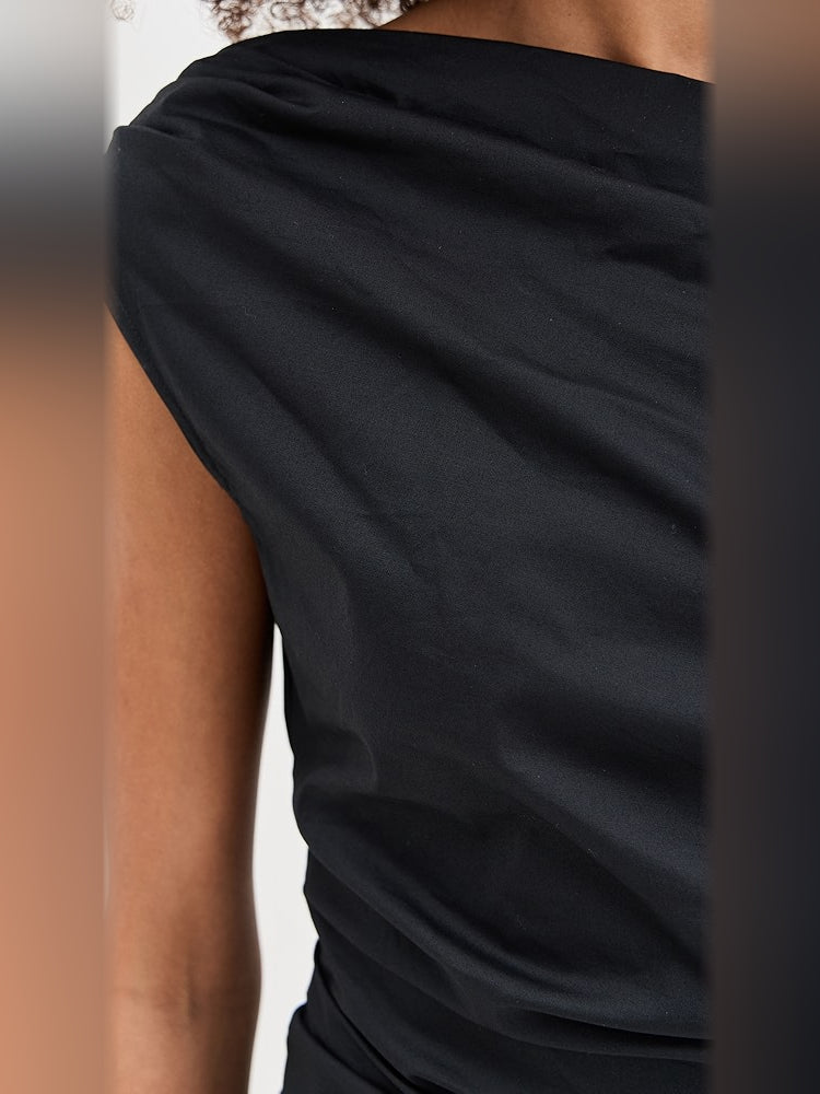 Black one-shoulder dress close-up showing draped sleeve and ruched waist