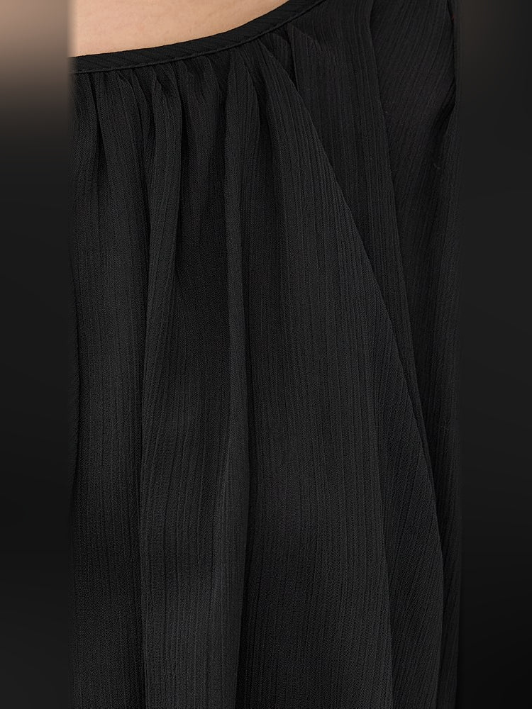 Black sheer fabric panel with subtle vertical pleats on the dress sleeve