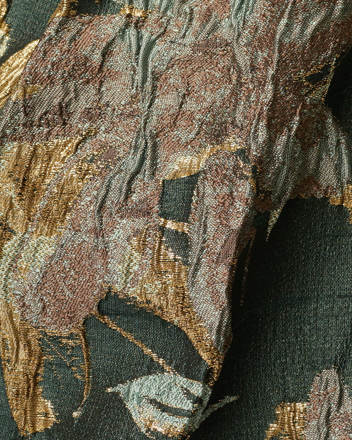 Close-up of gold and green botanical textured fabric on the draped bodice