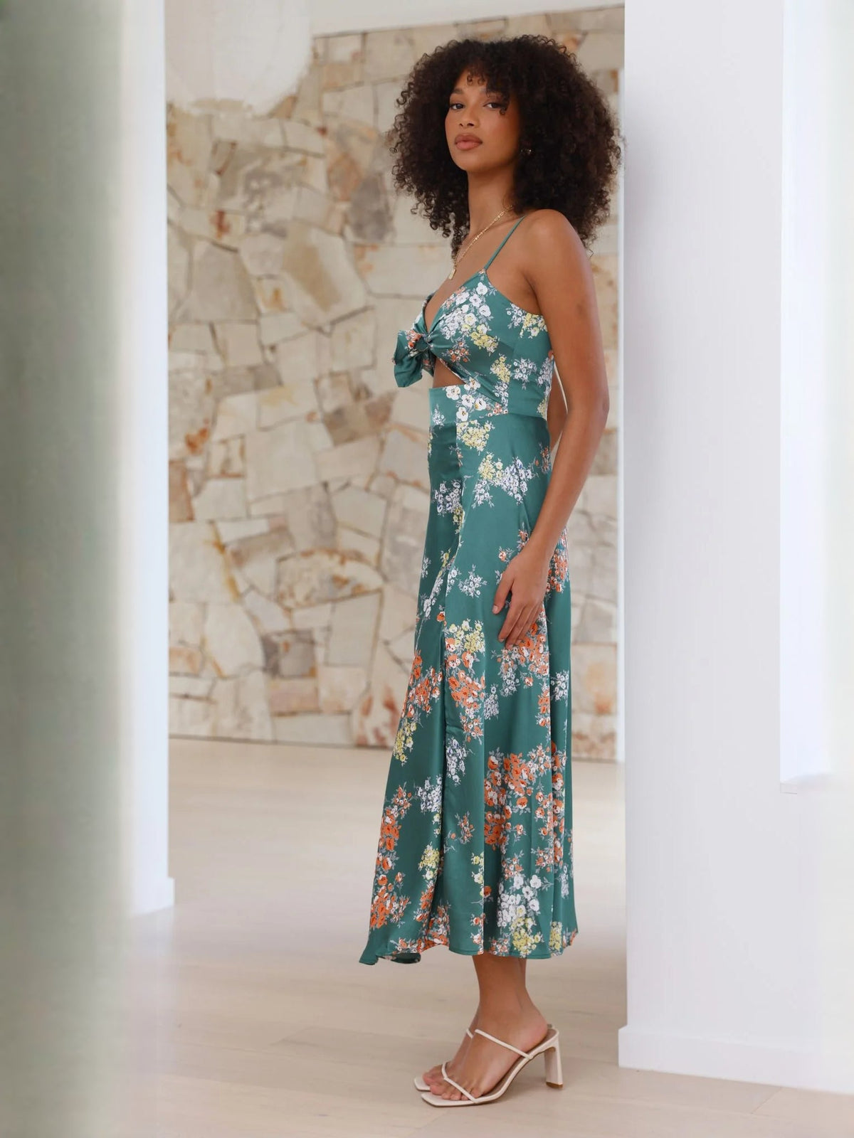 Side view of green floral midi dress with spaghetti straps and bow-tie front