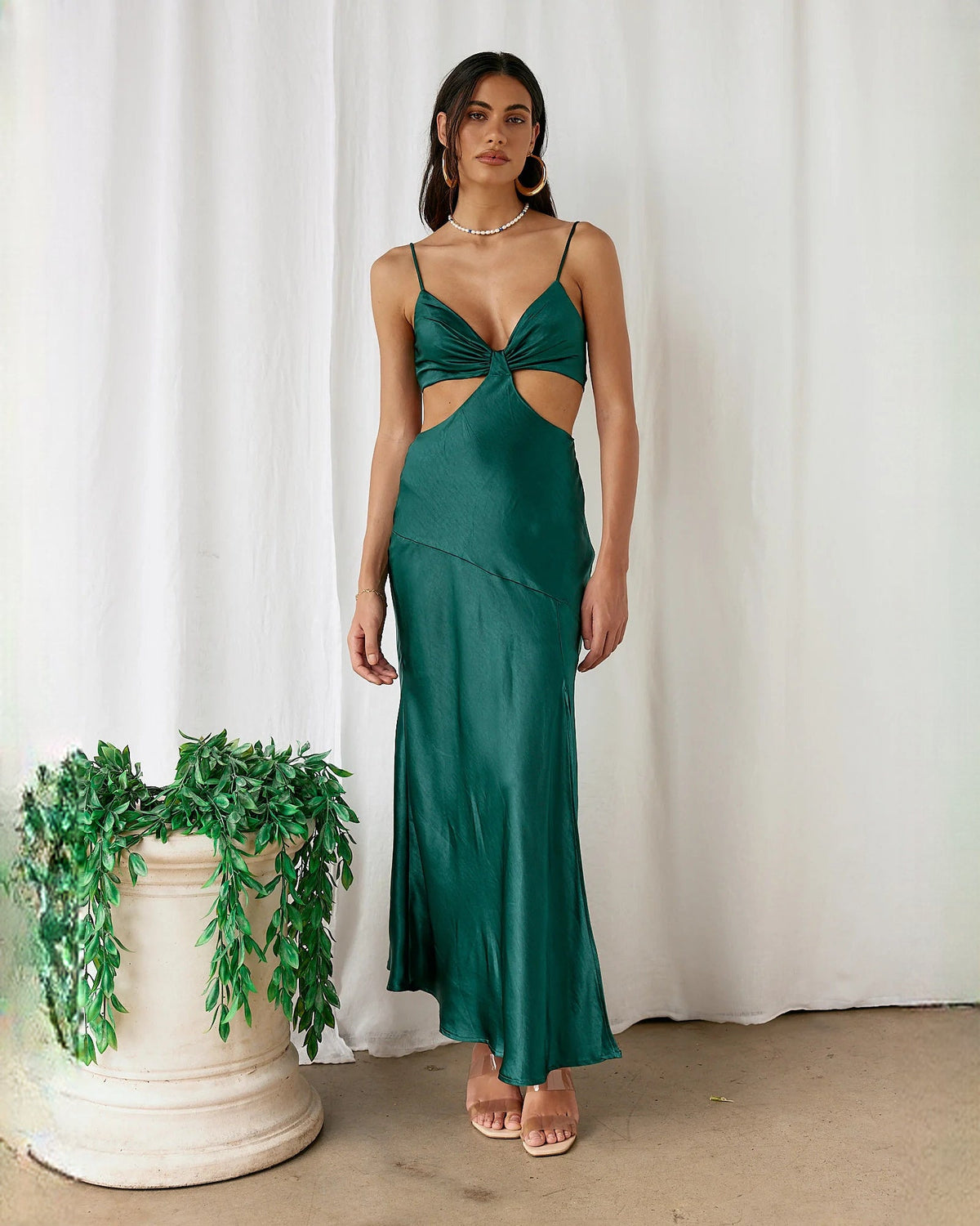 Emerald green satin sleeveless maxi dress with twisted sweetheart bodice and flowing A-line skirt.