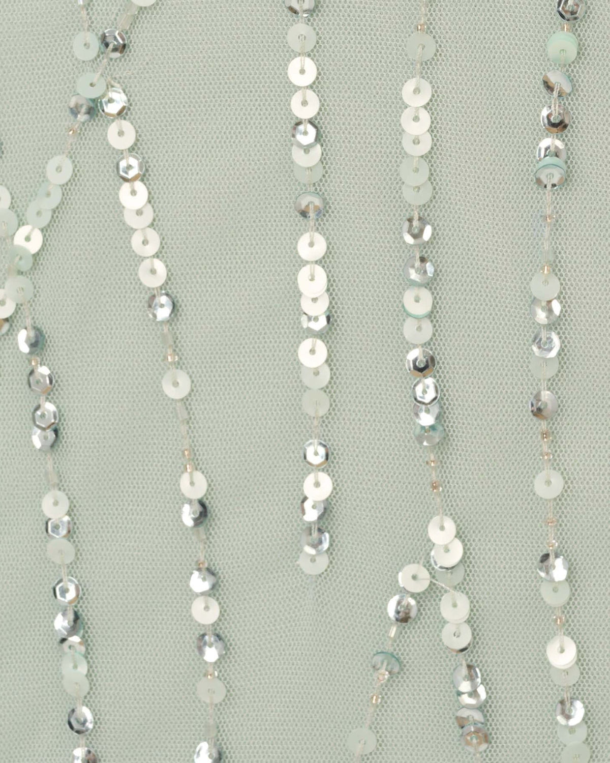 Close-up of mint green mesh fabric with long silver sequin fringe strands