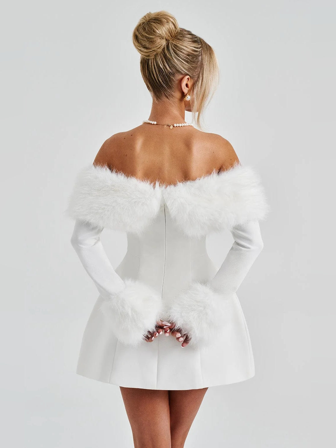 Back view of ivory mini dress with off-shoulder faux fur trim and gathered waist.
