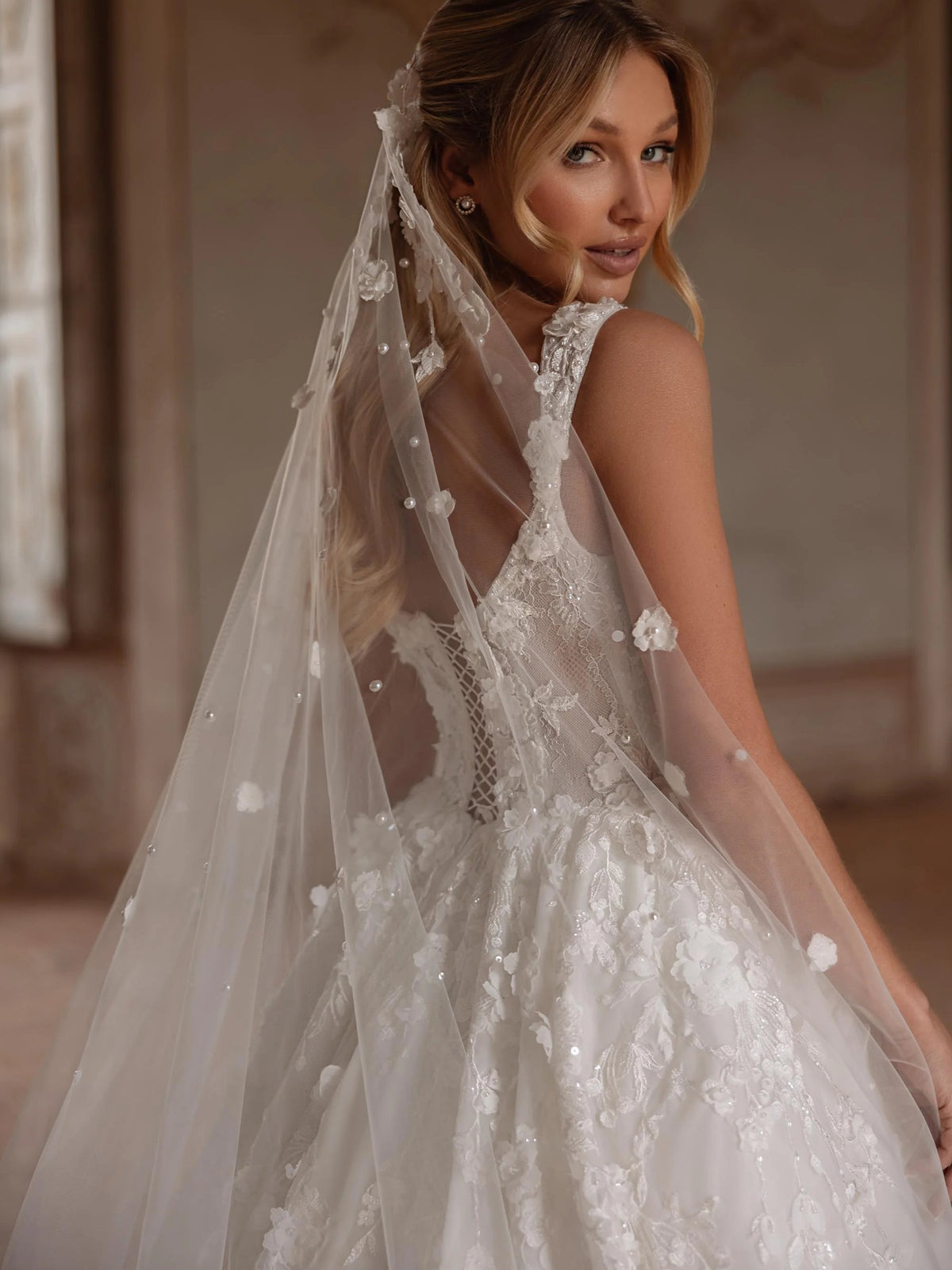 Ivory lace V-neck corset wedding dress with beaded veil overlay and floral details, close-up
