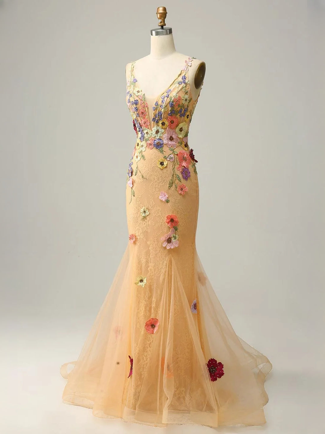 Peach tulle mermaid gown on mannequin with floral appliques and sheer ruffle hem