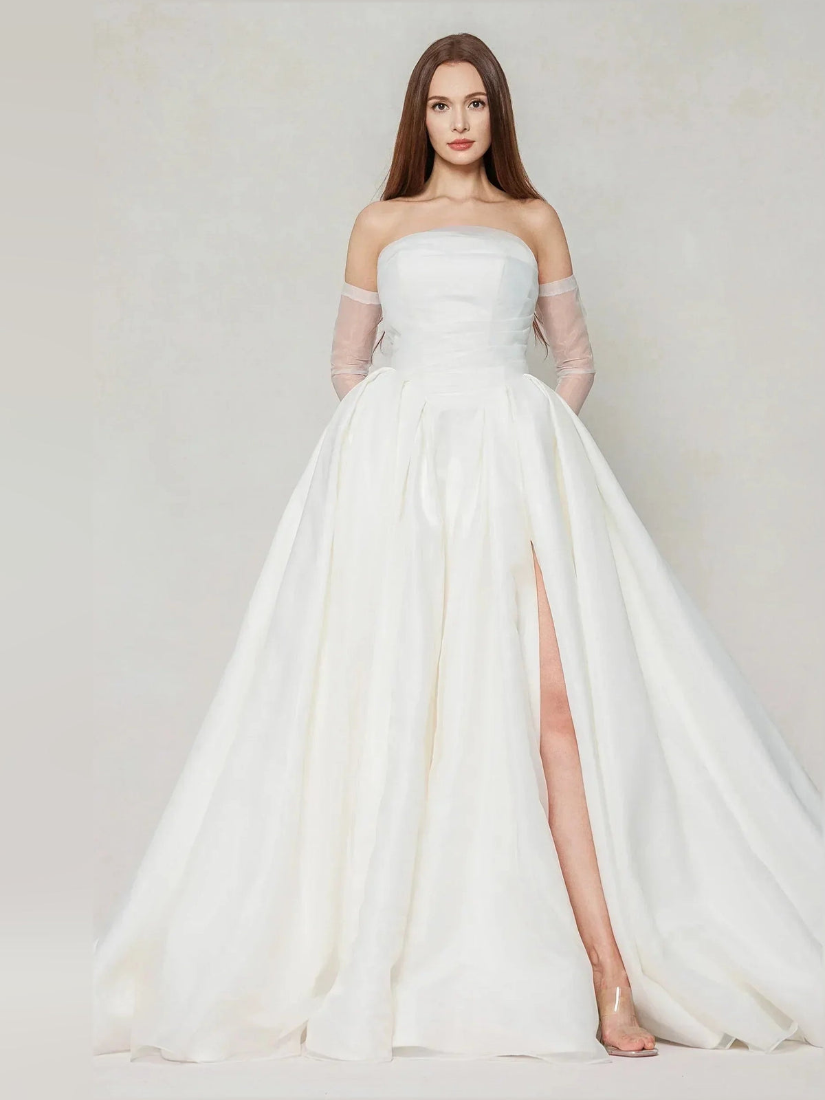 Ivory strapless ball gown with structured bodice, pleated skirt, and side slit