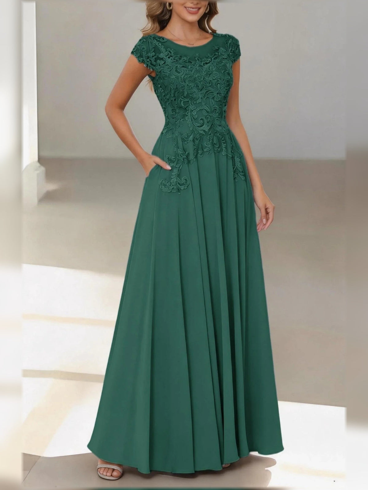 Emerald green satin A-line dress with lace cap sleeves and pleated floor-length skirt