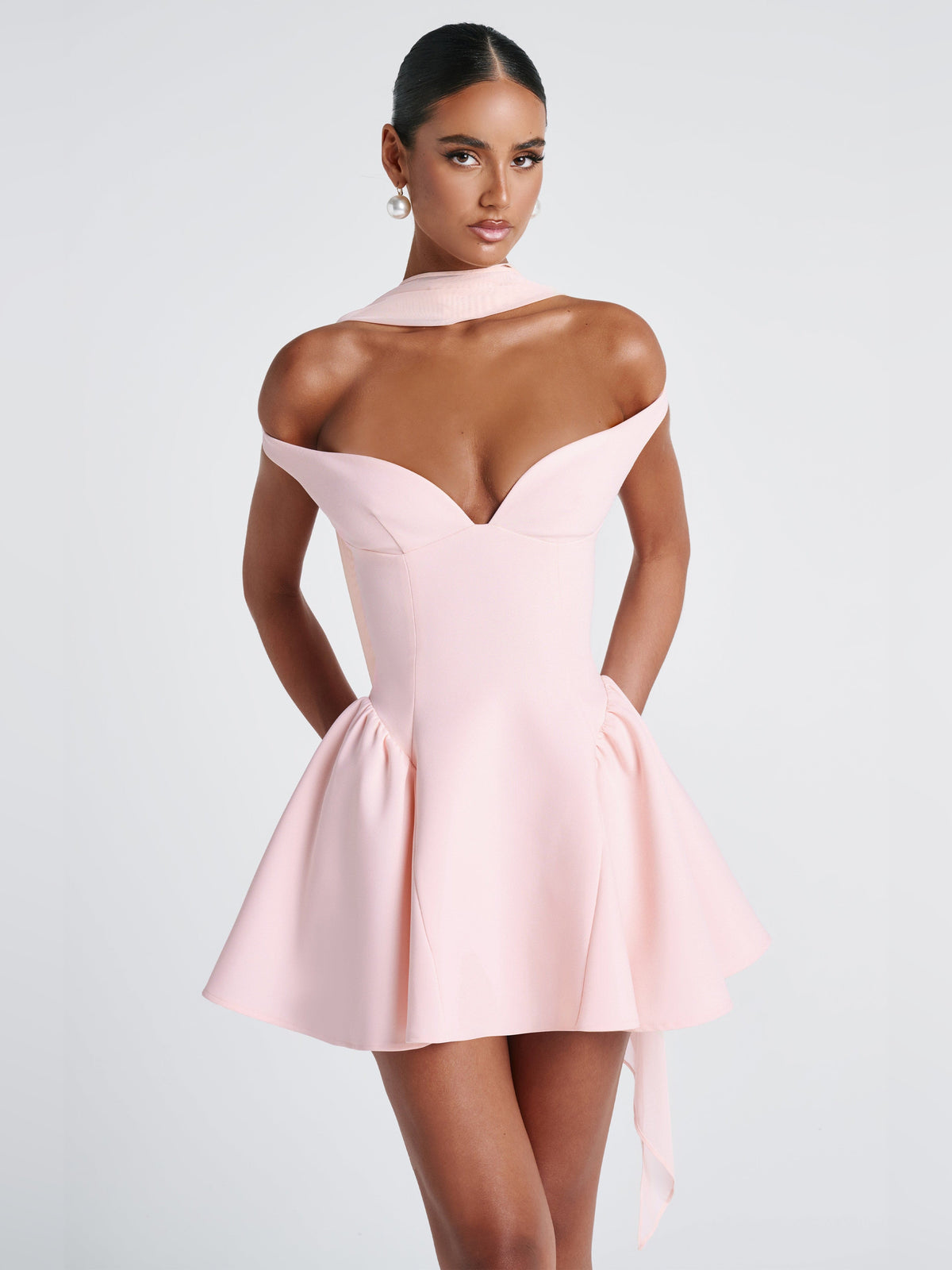 Blush mini dress from back: sweetheart bodice, gathered waist, flared skirt, long trailing chiffon ribbon.