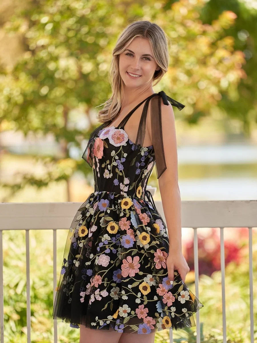 Black floral mini tulle dress with square neckline, corset-style bodice, tiered skirt.