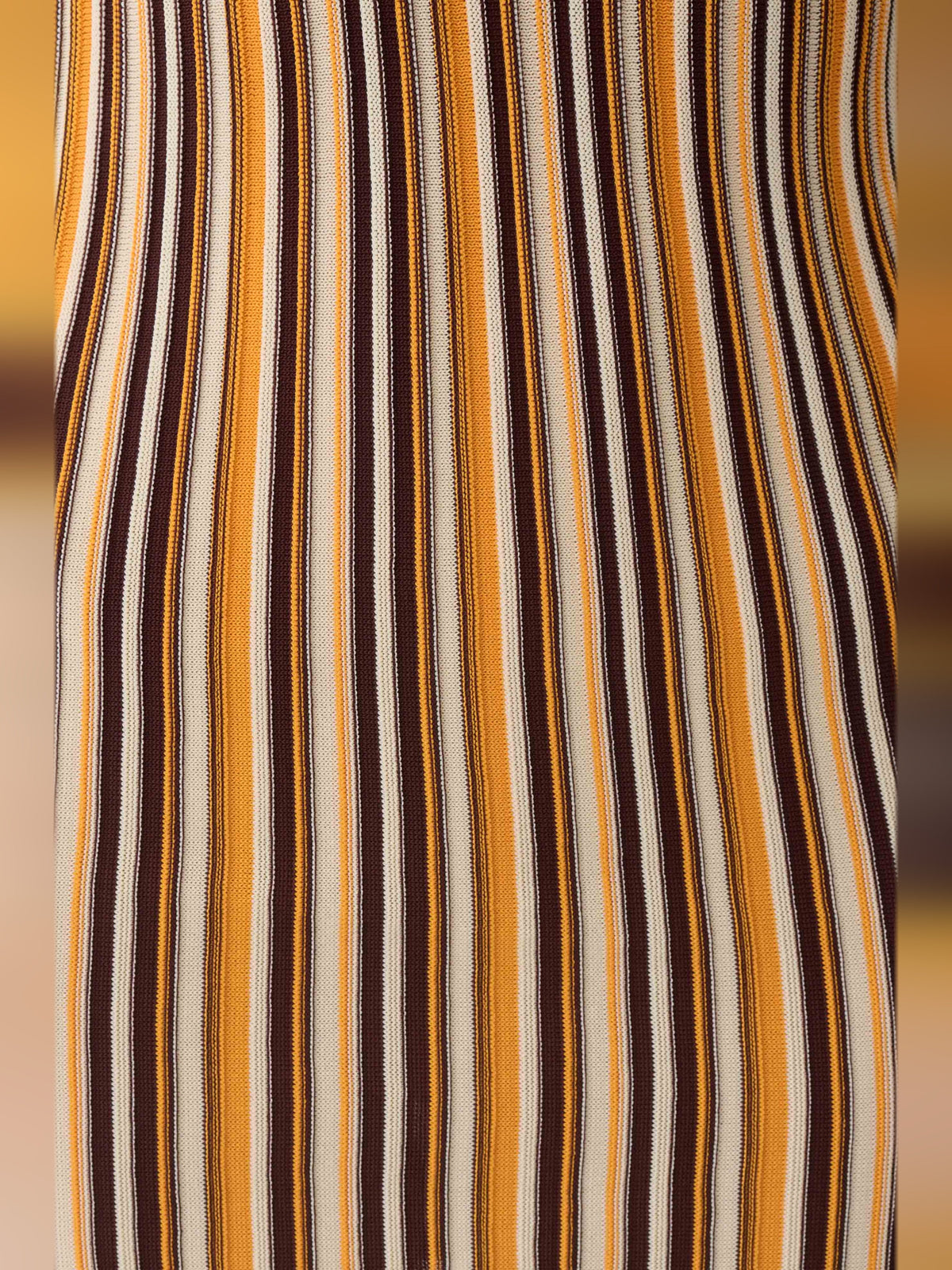 Close-up of vertical striped fabric on a sleeveless mini dress, brown, cream, and dark lines