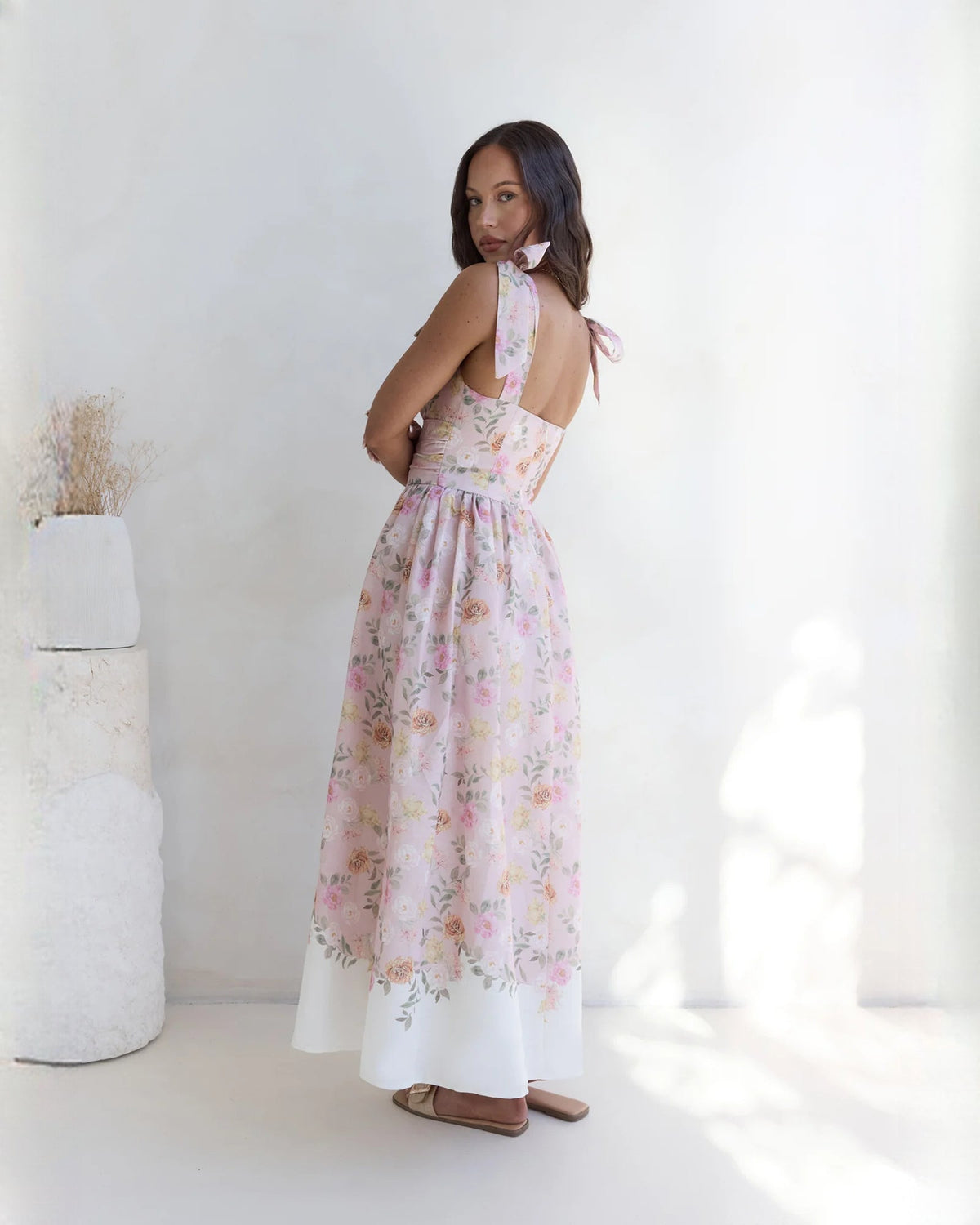 Side view of pink floral sleeveless satin A-line maxi dress with flowy tiered hem
