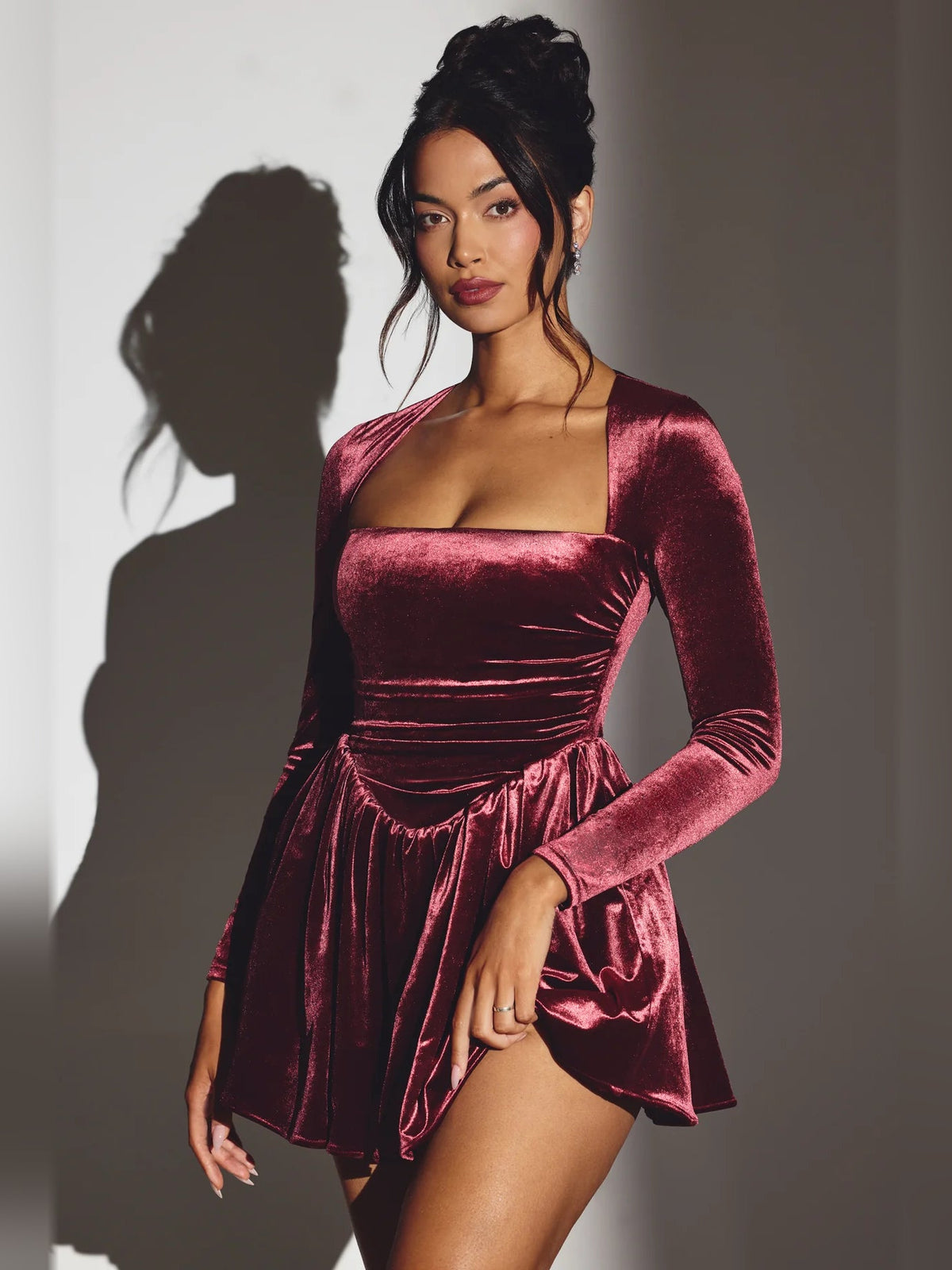 Wine velvet mini dress with long sleeves, corset ruching at waist, flared skirt.