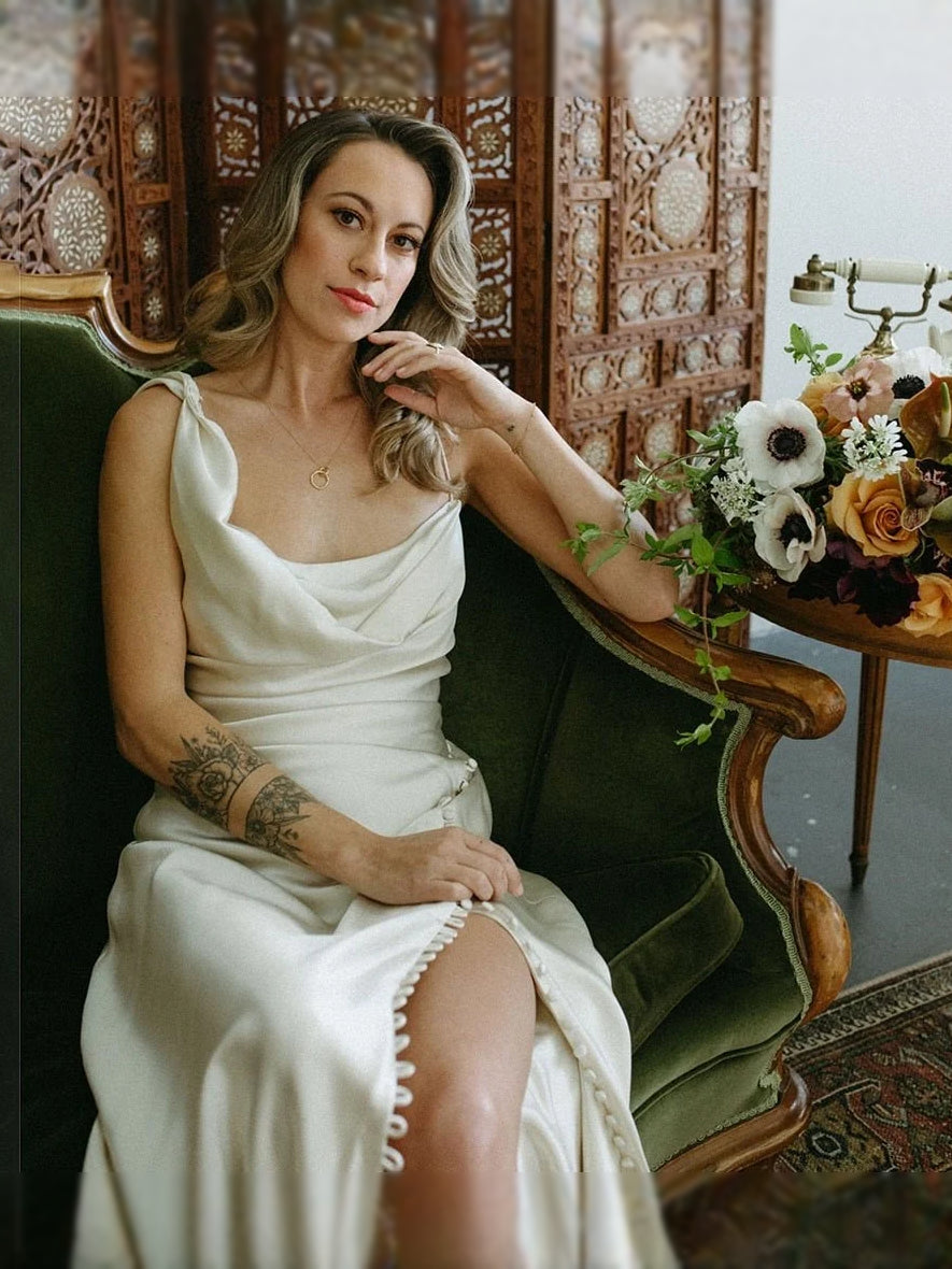 Ivory satin mermaid maxi dress with thin straps, draped corset, and floral bouquet