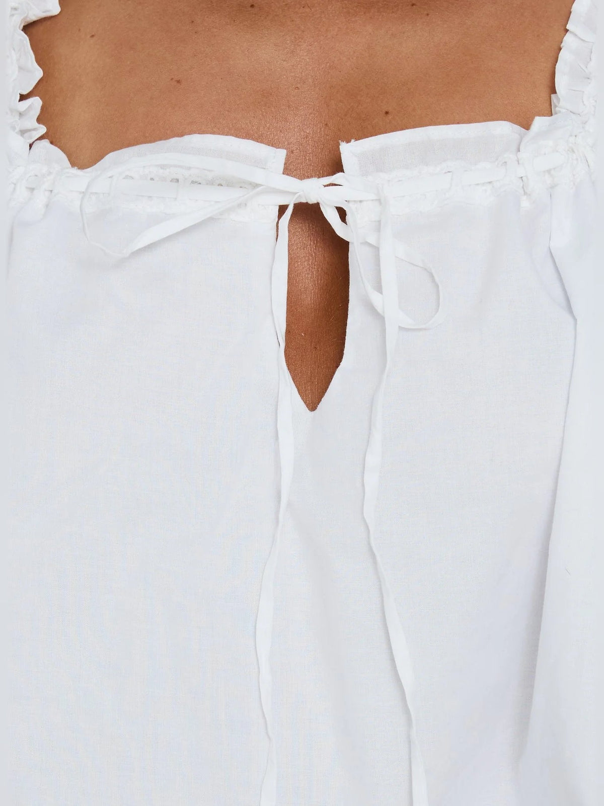 Close-up of white back bodice with ruffled edge and tied waist straps