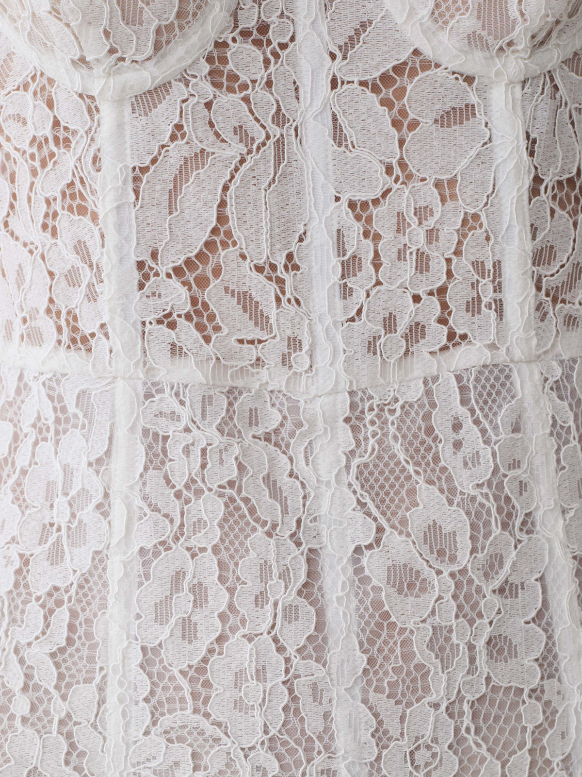 Close-up of white lace mesh overlay with floral openwork pattern