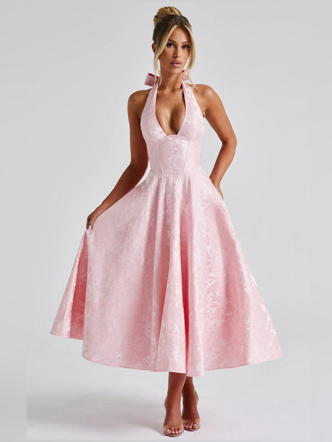 Front view of blush halter midi formal dress with deep V neckline and flowing flared skirt
