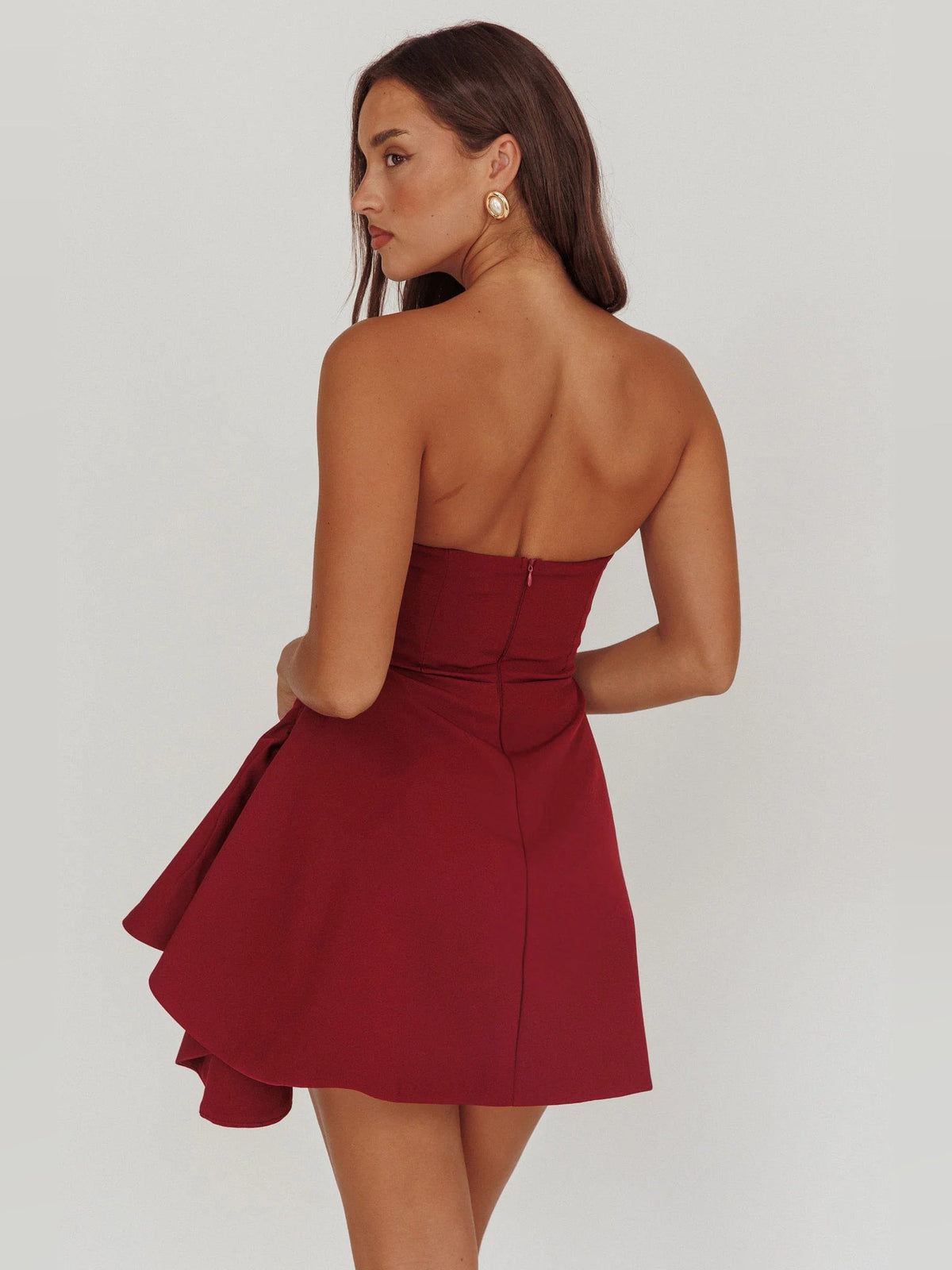Wine strapless mini dress from back, gathered seams and flared side hem