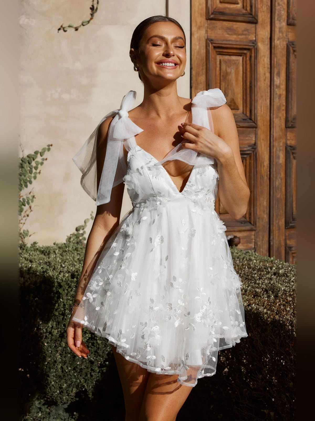 White mini homecoming dress with deep V neckline, sheer bow straps, layered tulle skirt