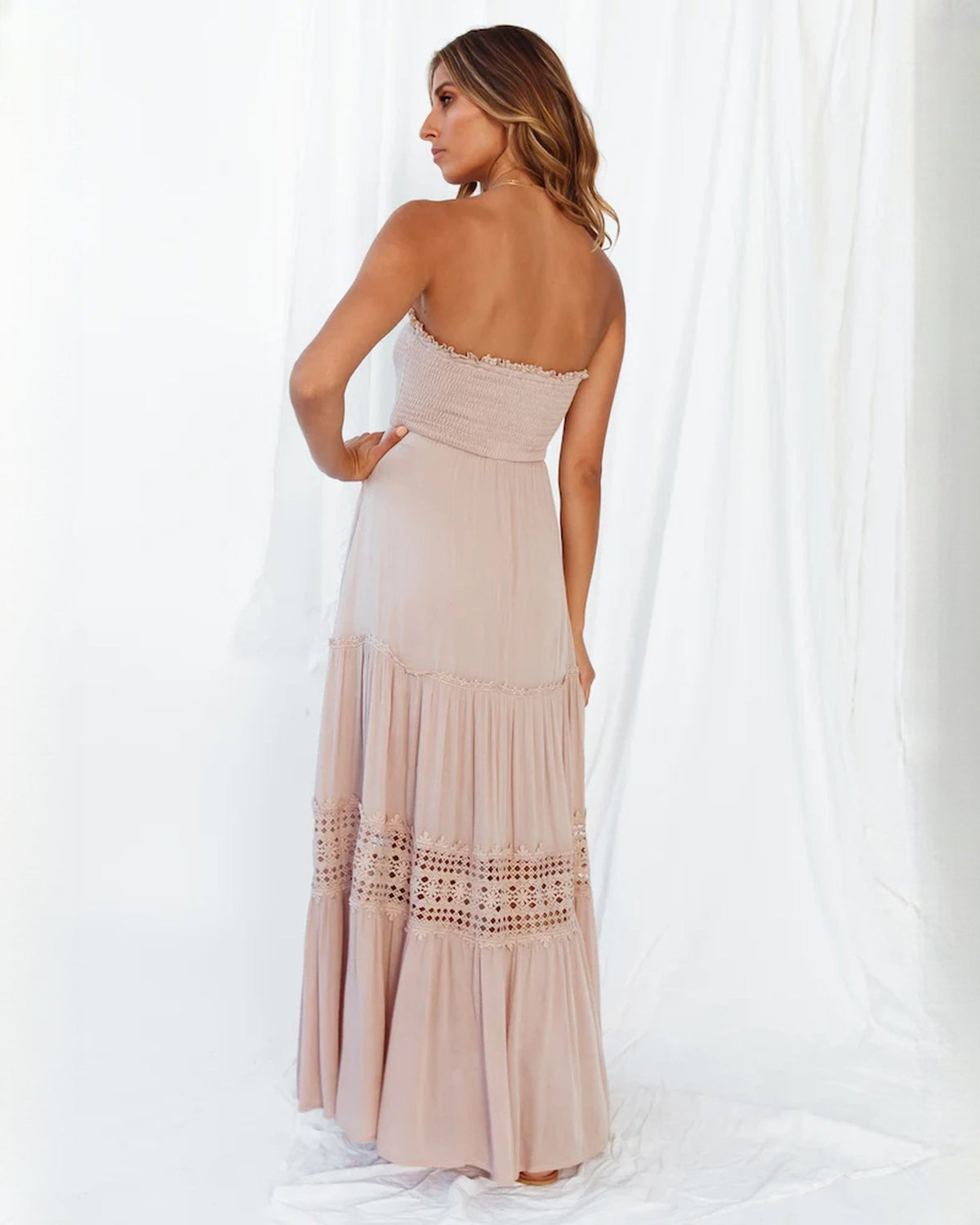 Blush pink A-line maxi dress shown from the back, with tiered skirt and lace trim