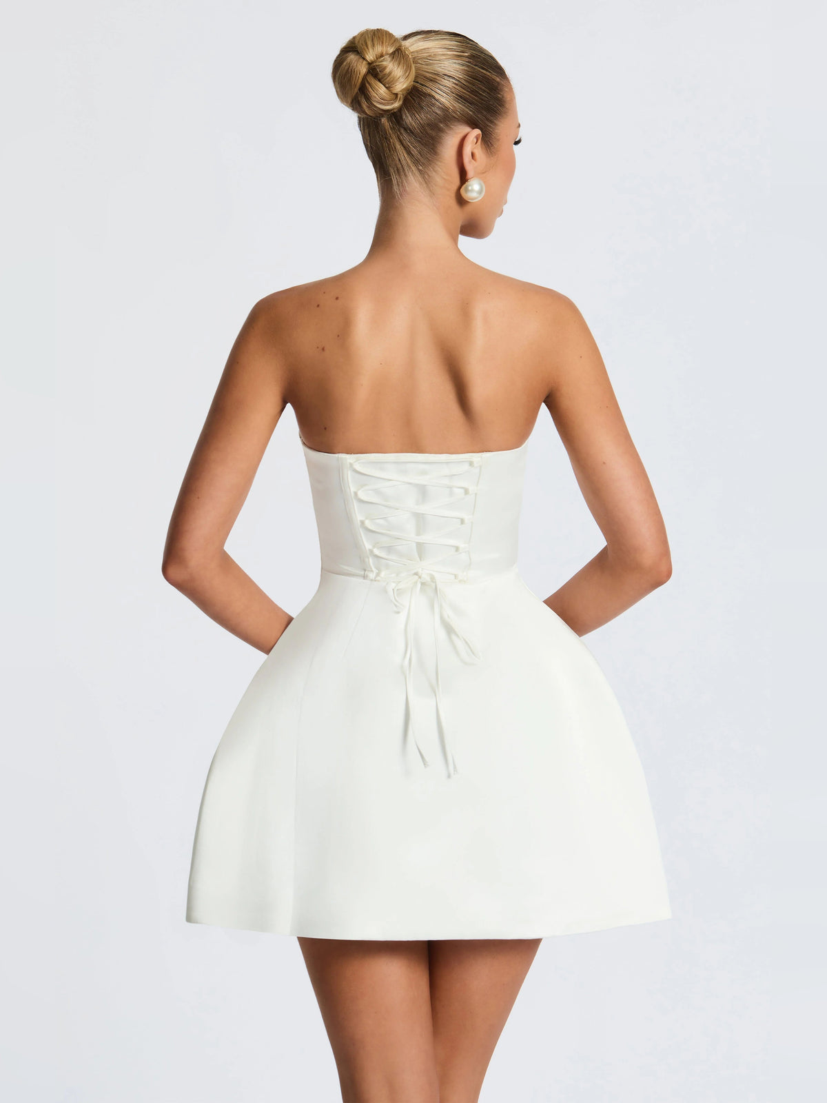 Ivory mini strapless dress with lace-up back bodice and tied waist bow, back view.