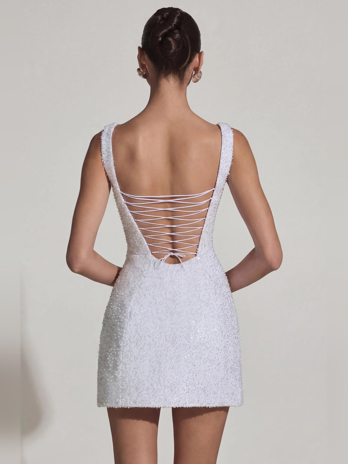 White mini dress open-back design with crisscross lacing on straps, A-line cut.