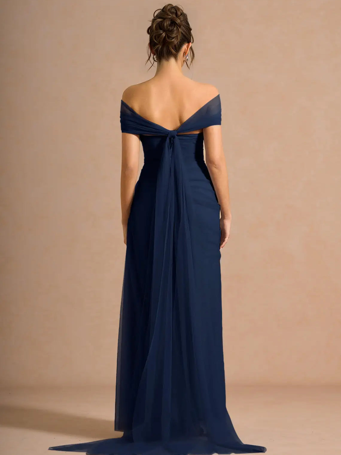 Off-shoulder formal dress in navy blue with open back draping and full-length skirt
