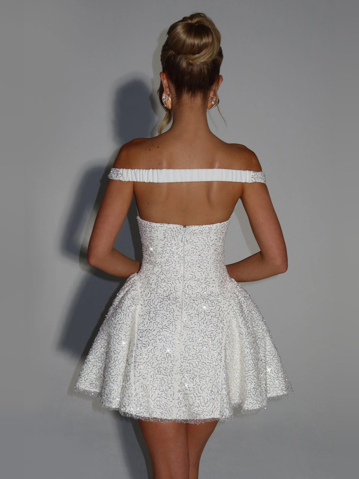 Ivory sequined off-shoulder mini dress from back, fitted waist, flared skirt hem